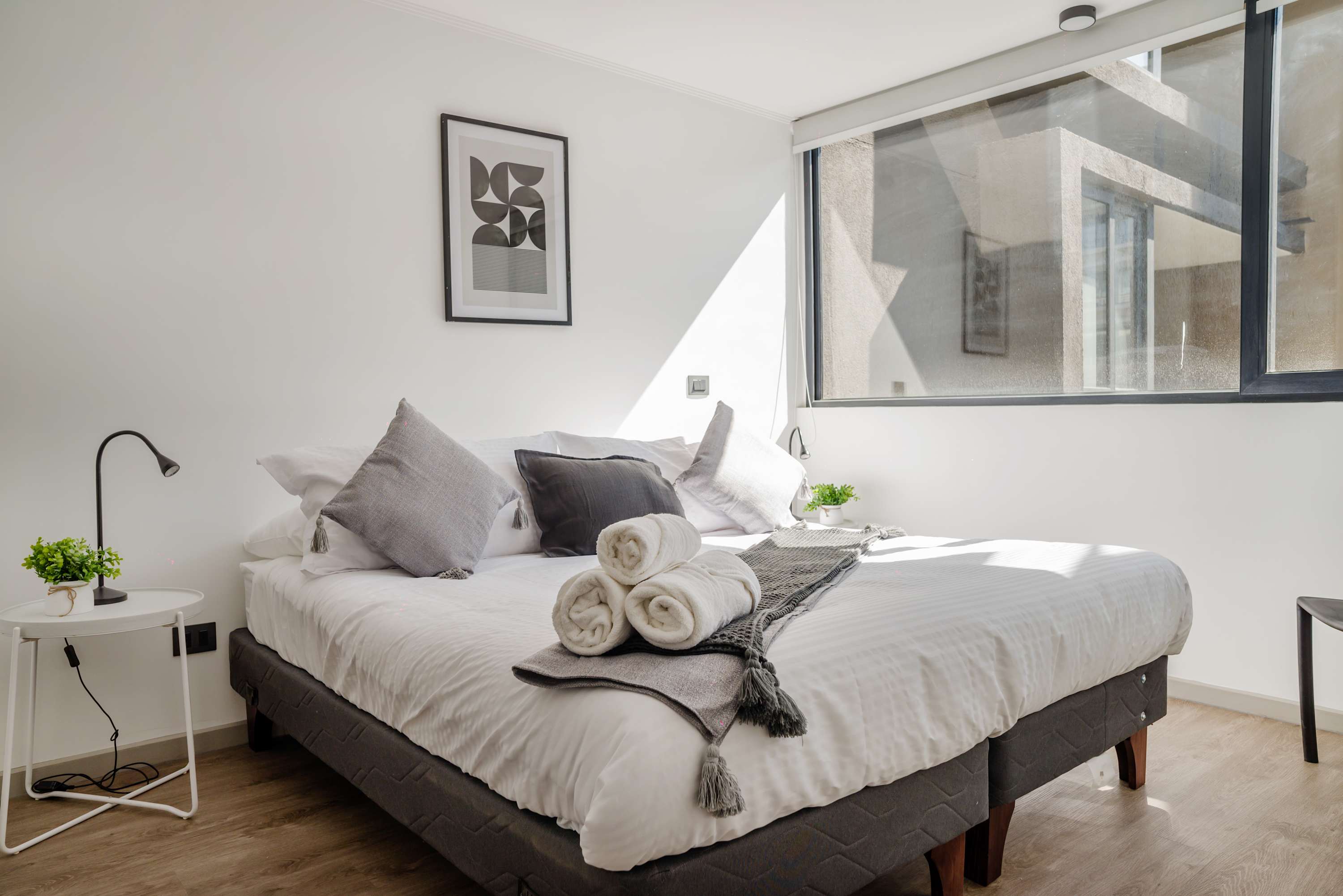 Relax in this bright and cozy bedroom with modern decor and ample natural light, perfect for unwinding after a day of exploring.