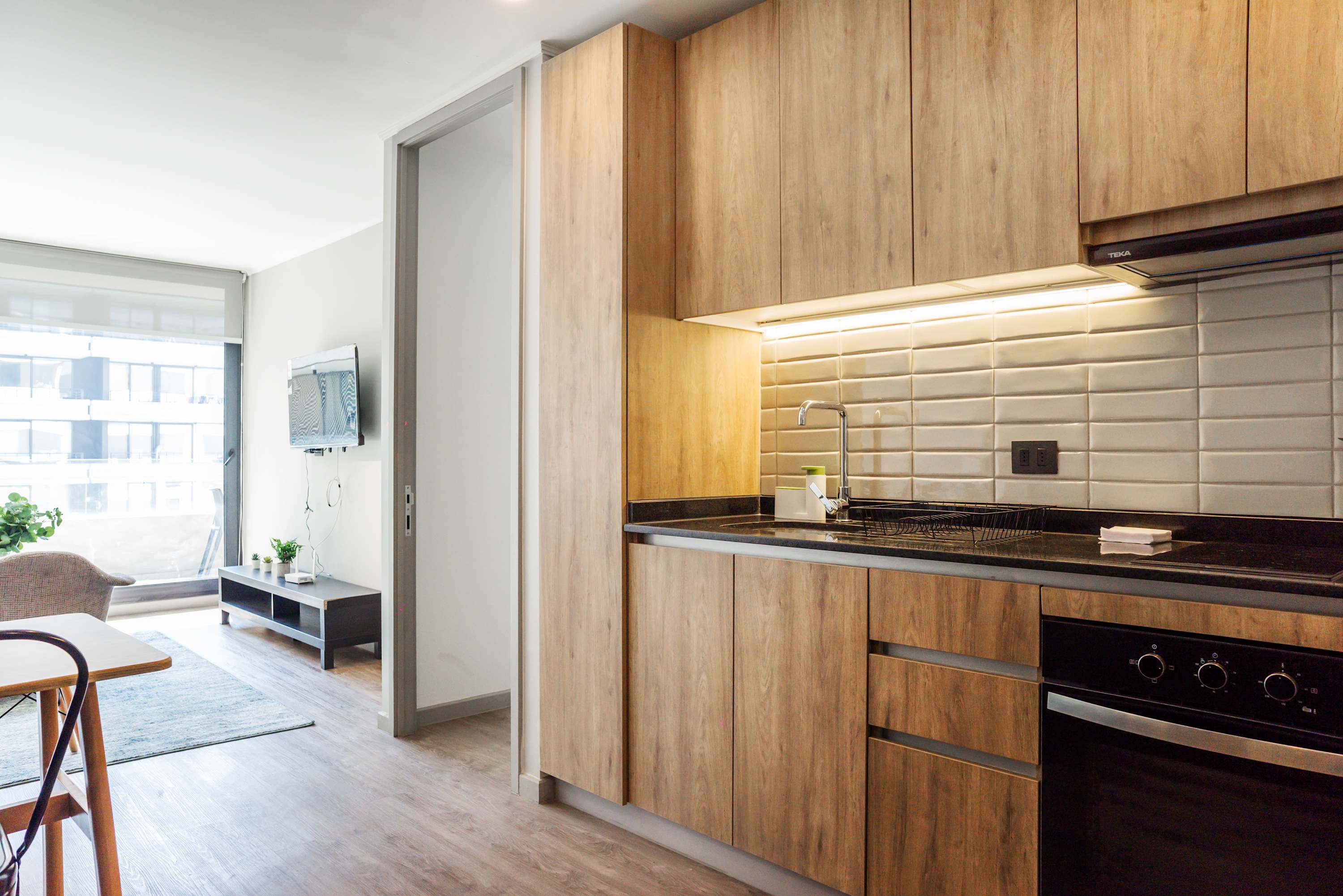Experience modern living with this stylish kitchen and cozy living area, bathed in natural light.