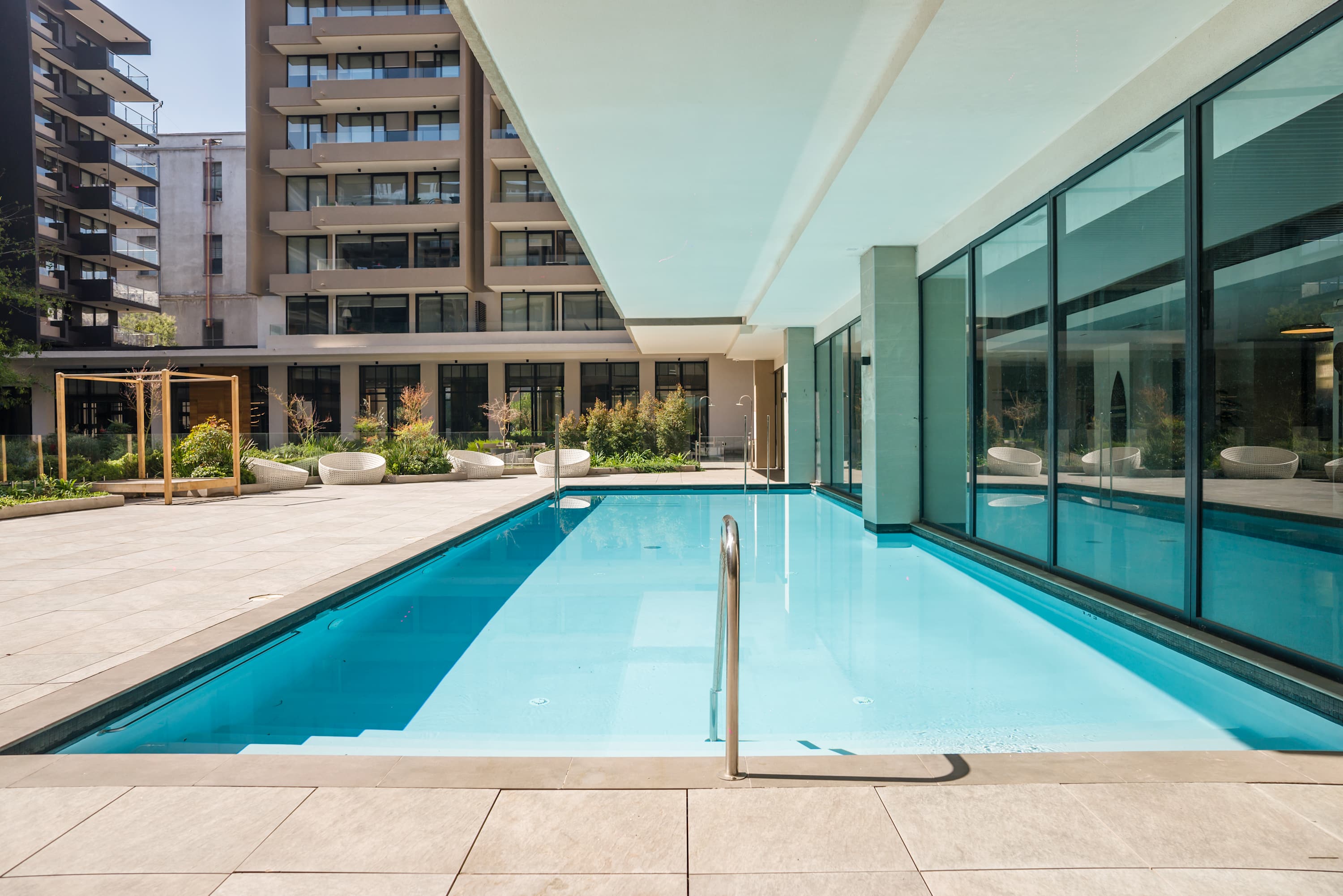 Enjoy a refreshing swim in the modern pool surrounded by lush greenery and contemporary design.