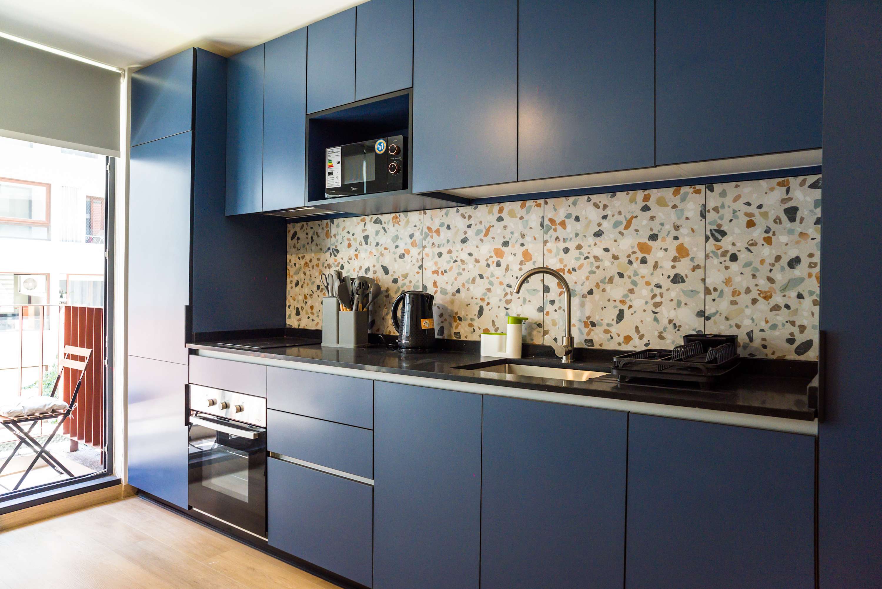 Modern kitchen with terrazzo backsplash and balcony access, perfect for a cozy breakfast or evening relaxation.