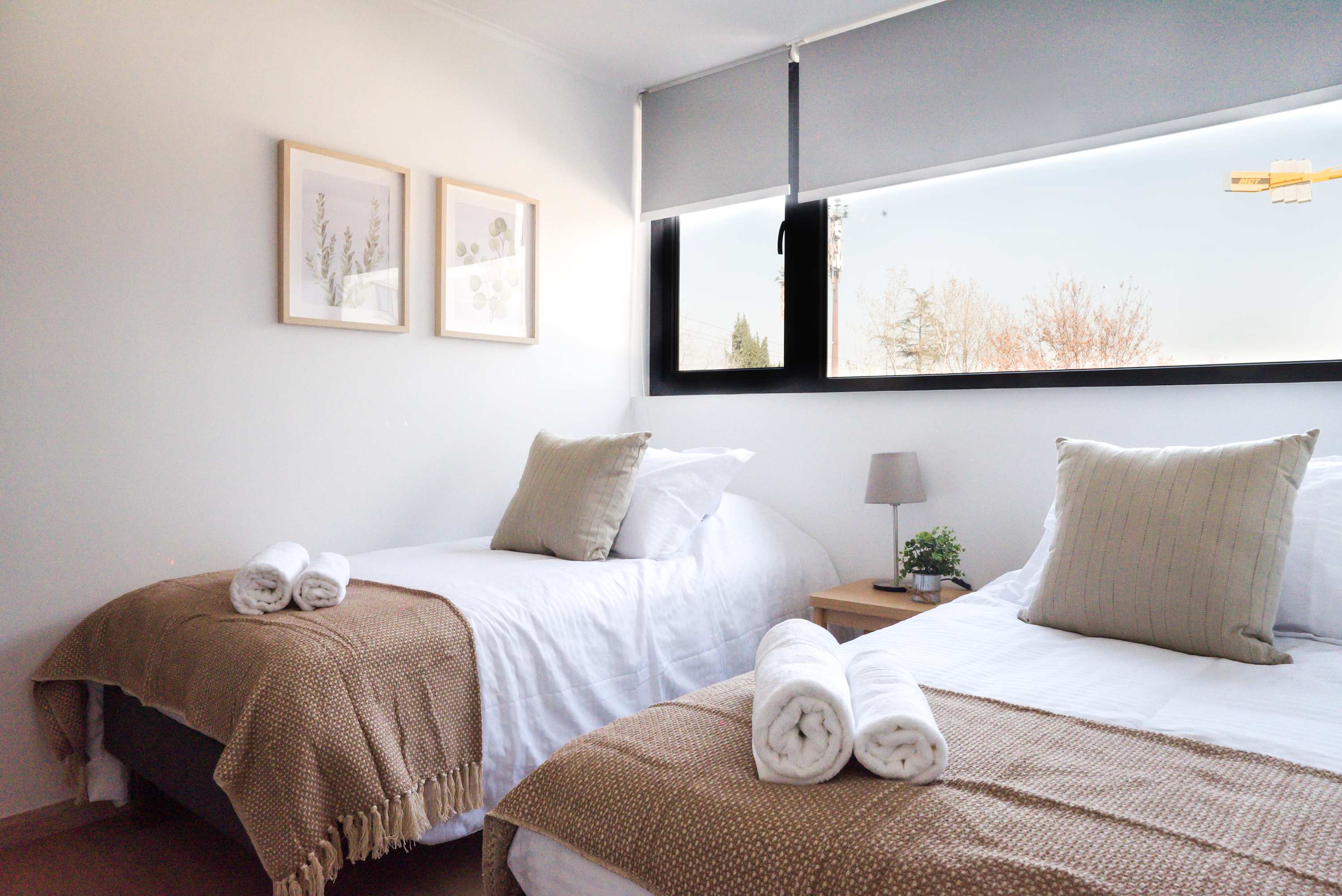 Bright twin bedroom with cozy decor and a serene view, perfect for a restful stay.