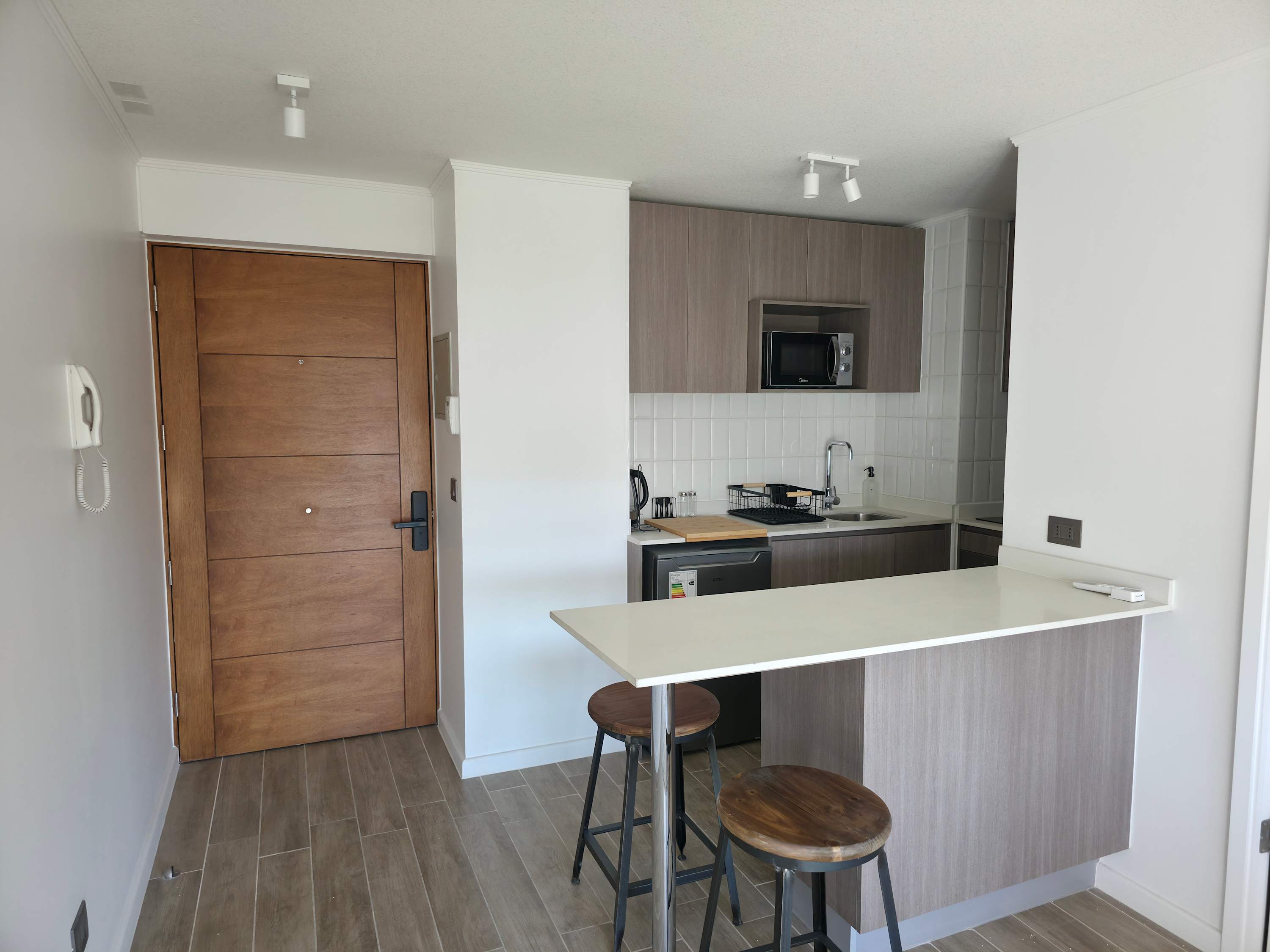 Modern kitchen with breakfast bar, ideal for quick meals or coffee breaks in a cozy studio setting.