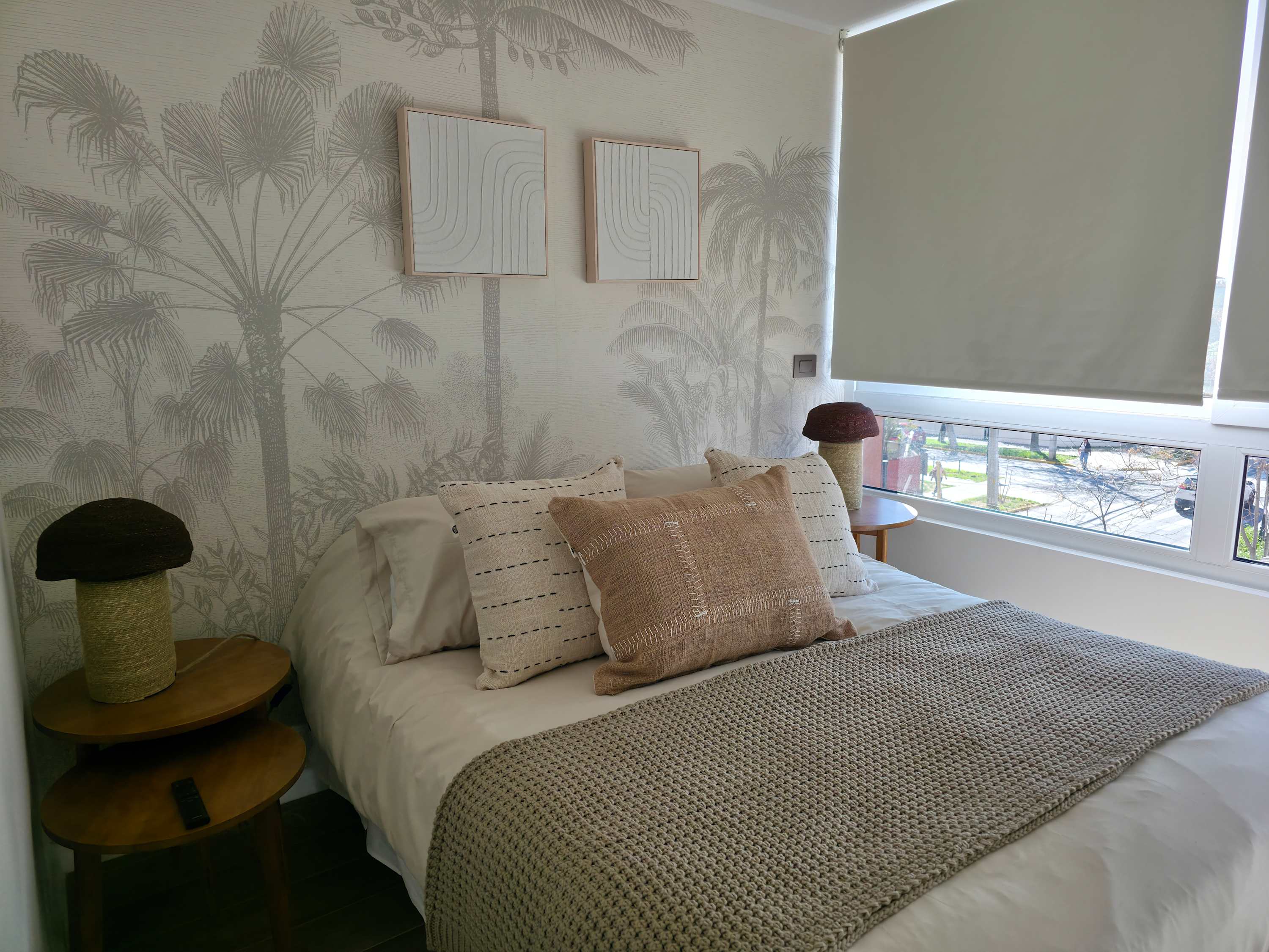 Unwind in this tranquil bedroom with a nature-themed mural and plush bedding, bathed in natural light from a large window.