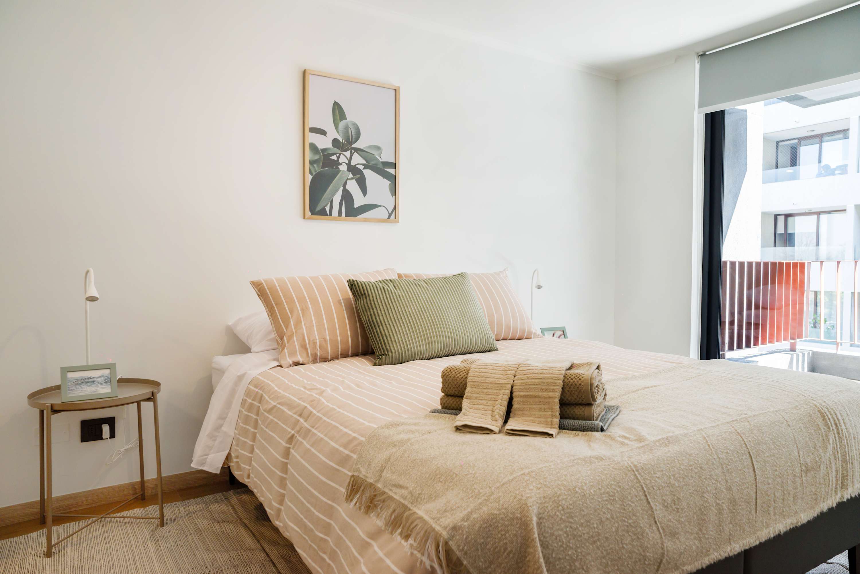 Enjoy a serene retreat in this sunlit bedroom with cozy bedding and modern decor, perfect for relaxation.
