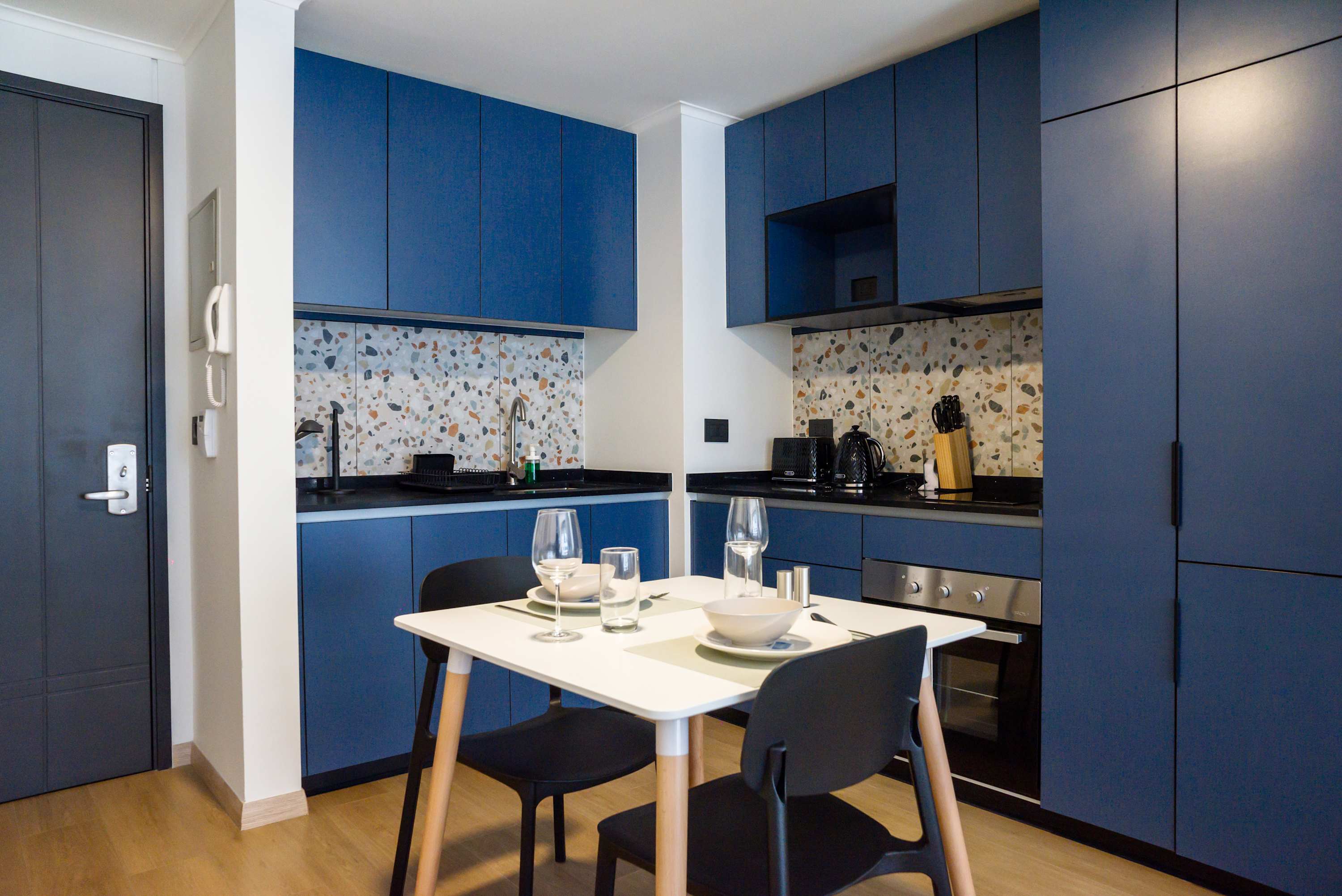 Modern kitchen with stylish blue cabinets and terrazzo accents, ideal for cozy meals in a chic setting.