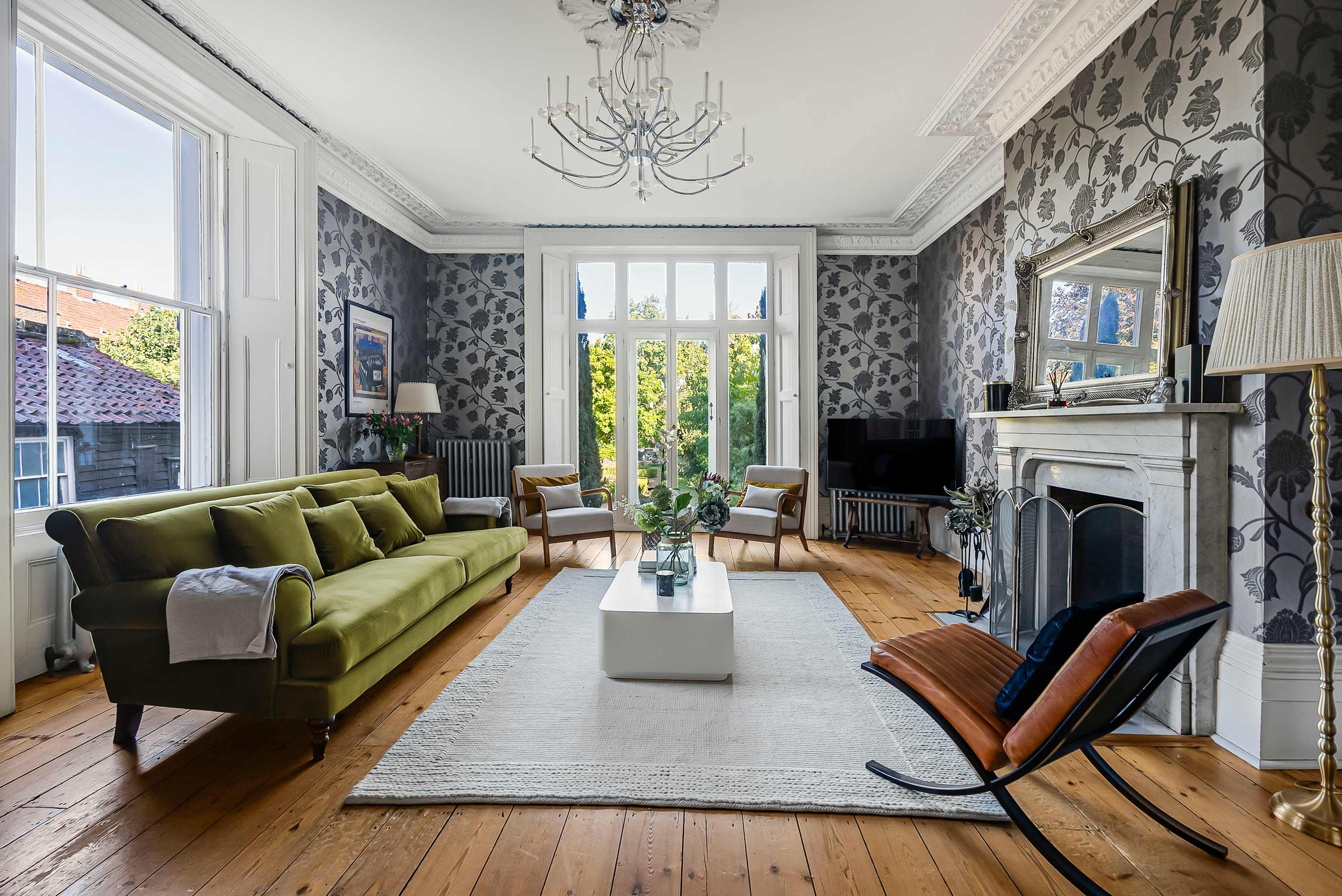 Green sofa and period fireplace in the sitting room at Squires House