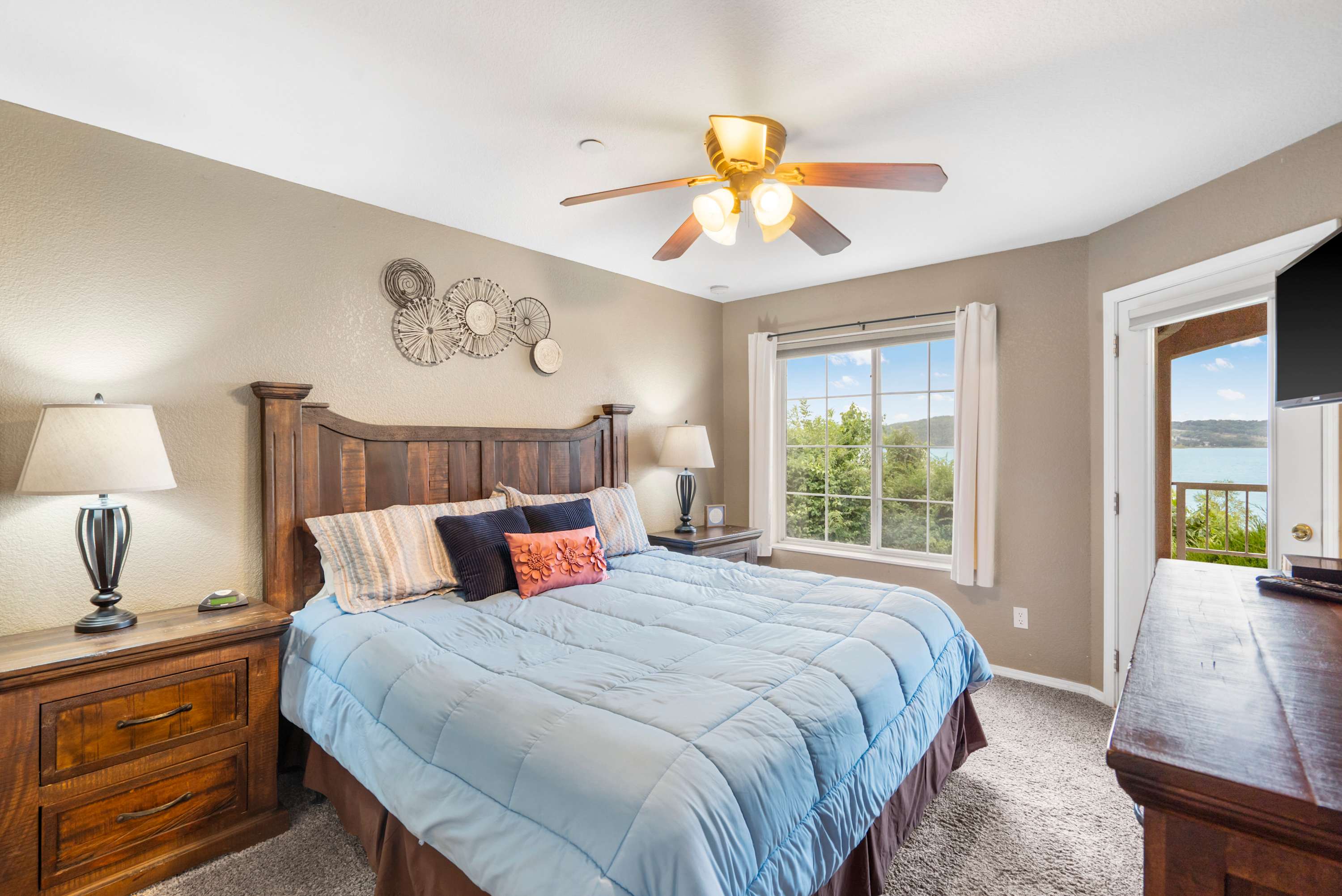 The primary king suite boasts a TV, an ensuite bath, & deck access​