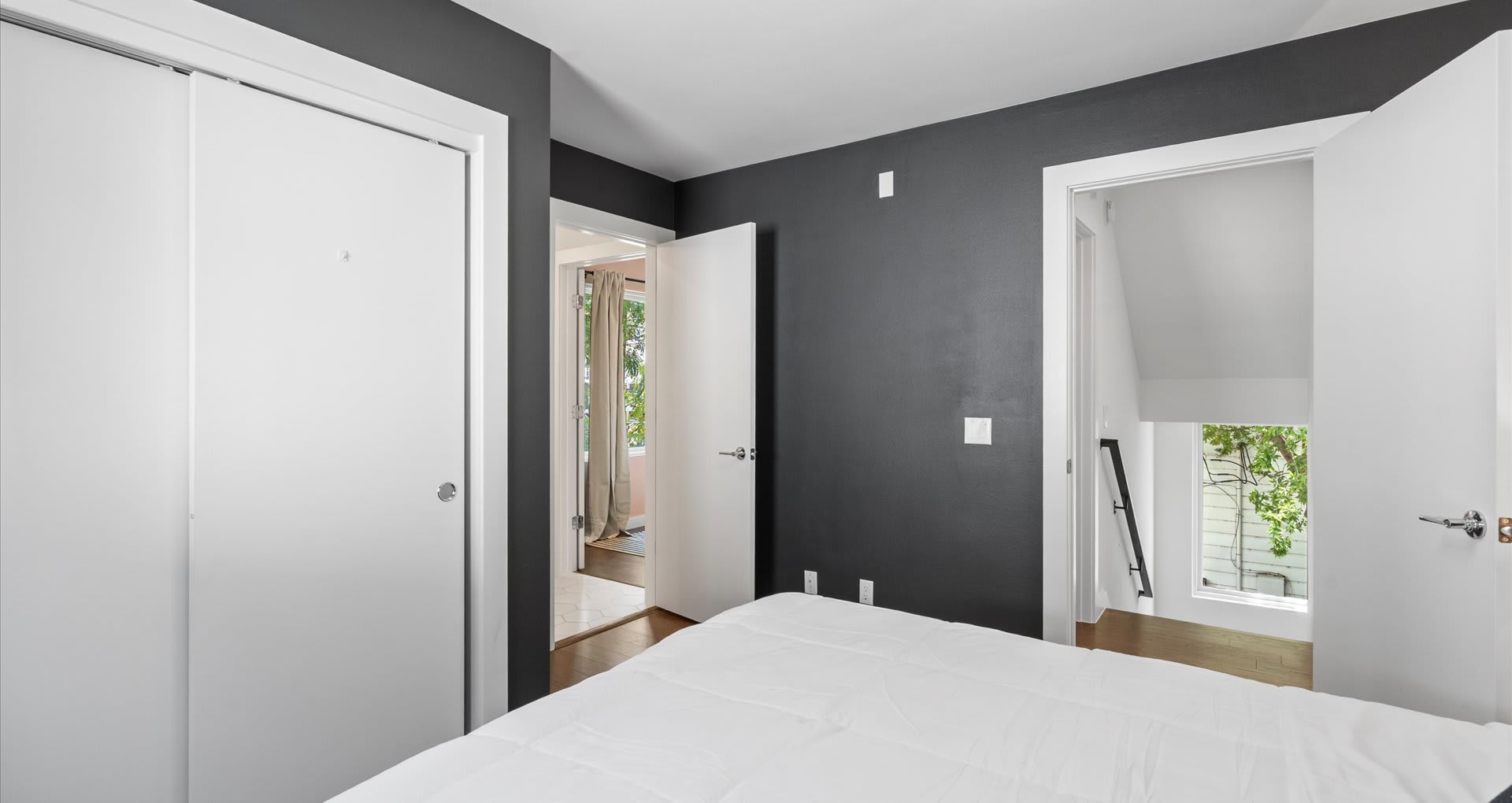 Chic queen bedroom designed in calming grey and white tones, accented with modern abstract wallpaper for a stylish yet relaxing retreat.