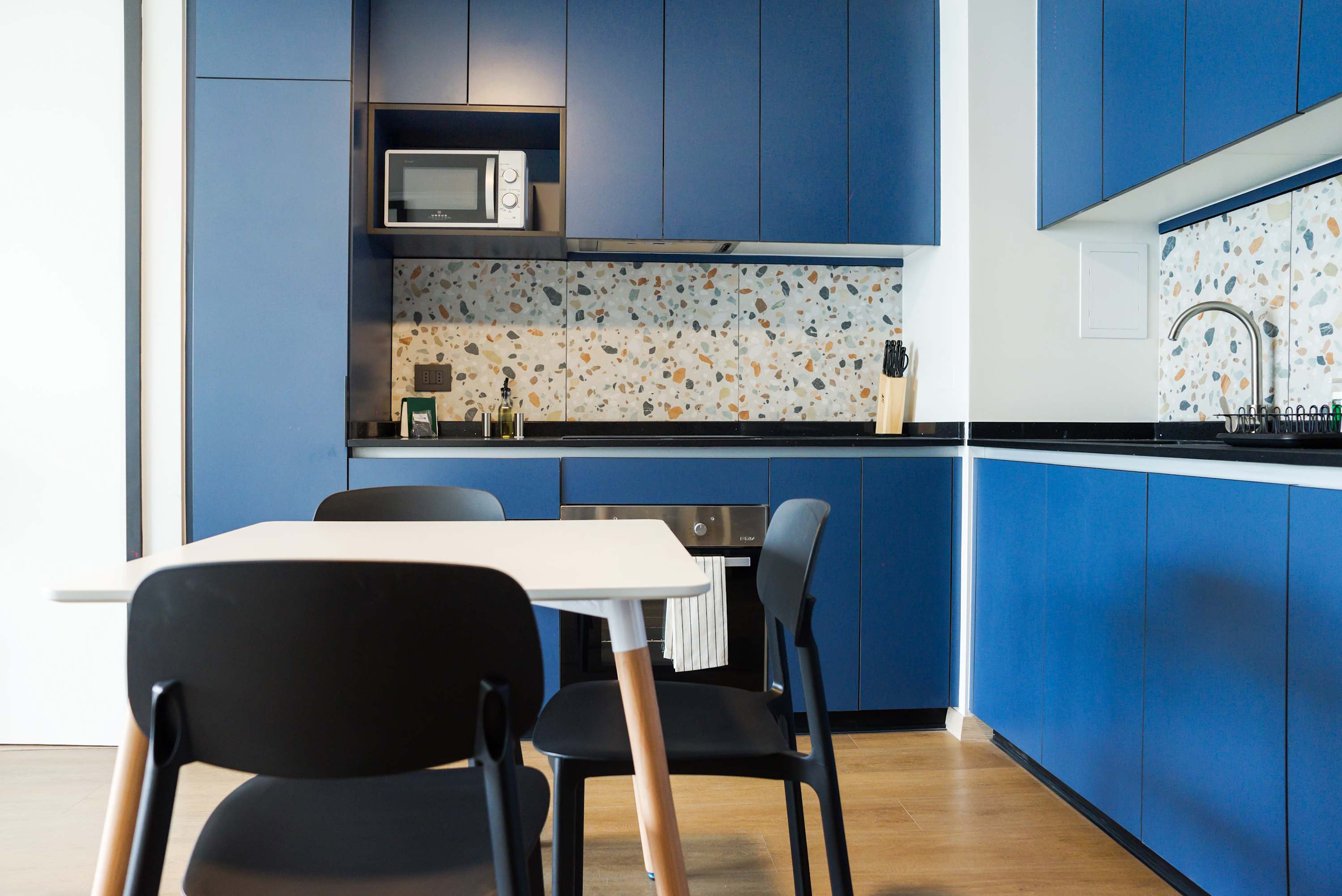Modern kitchen with vibrant blue cabinets and terrazzo backsplash, ideal for culinary adventures.
