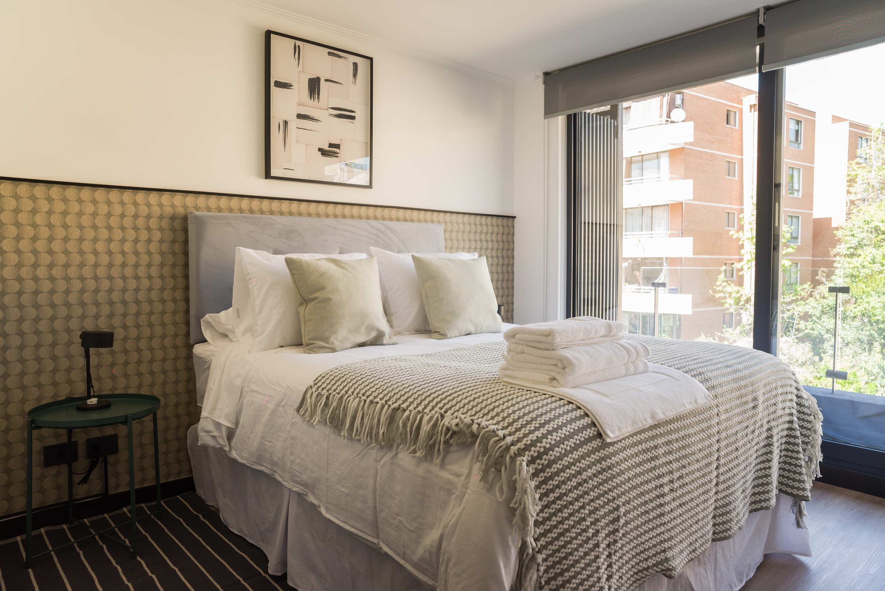 Cozy bedroom with modern decor and a large window offering a bright, inviting atmosphere.