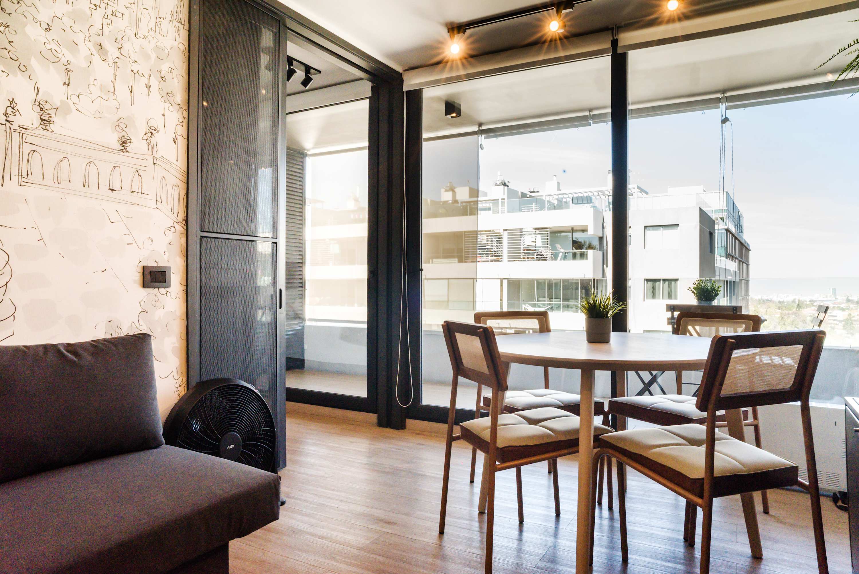 Enjoy dining with a view in this stylish apartment featuring floor-to-ceiling windows and artistic decor.