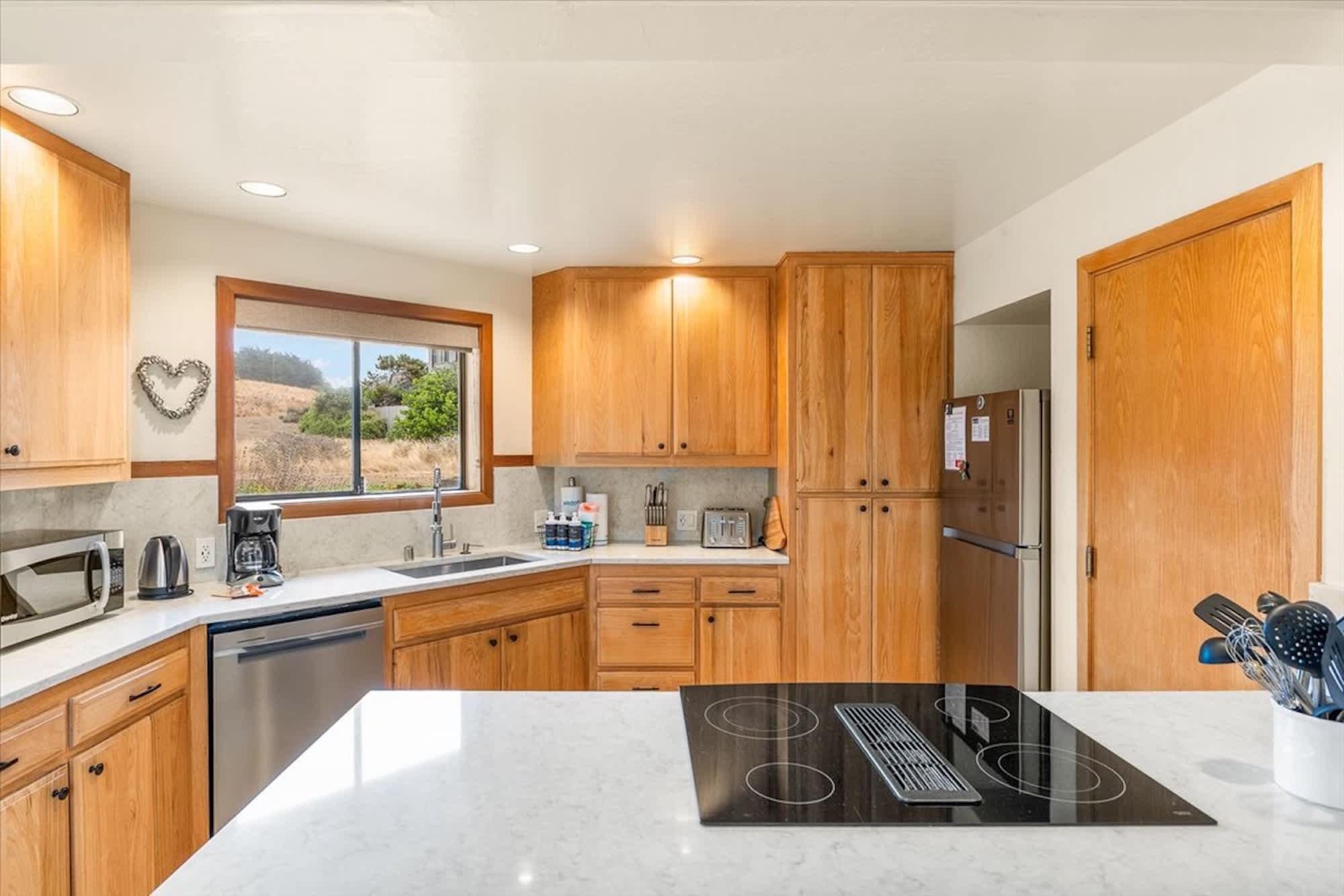 Fully stocked kitchen with bar seating, modern stovetop, and a view.