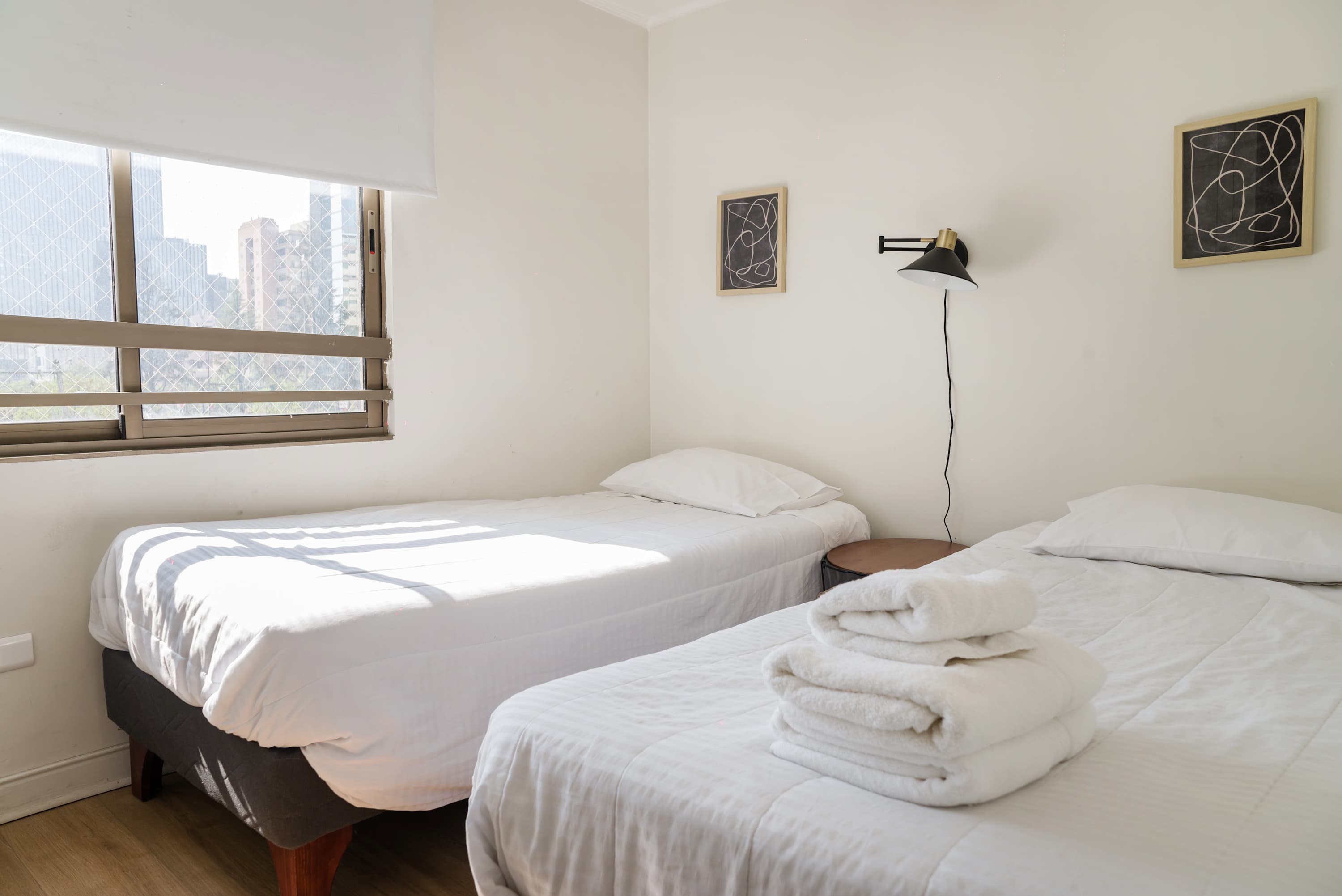 Bright bedroom with twin beds and city views, ideal for a cozy stay.