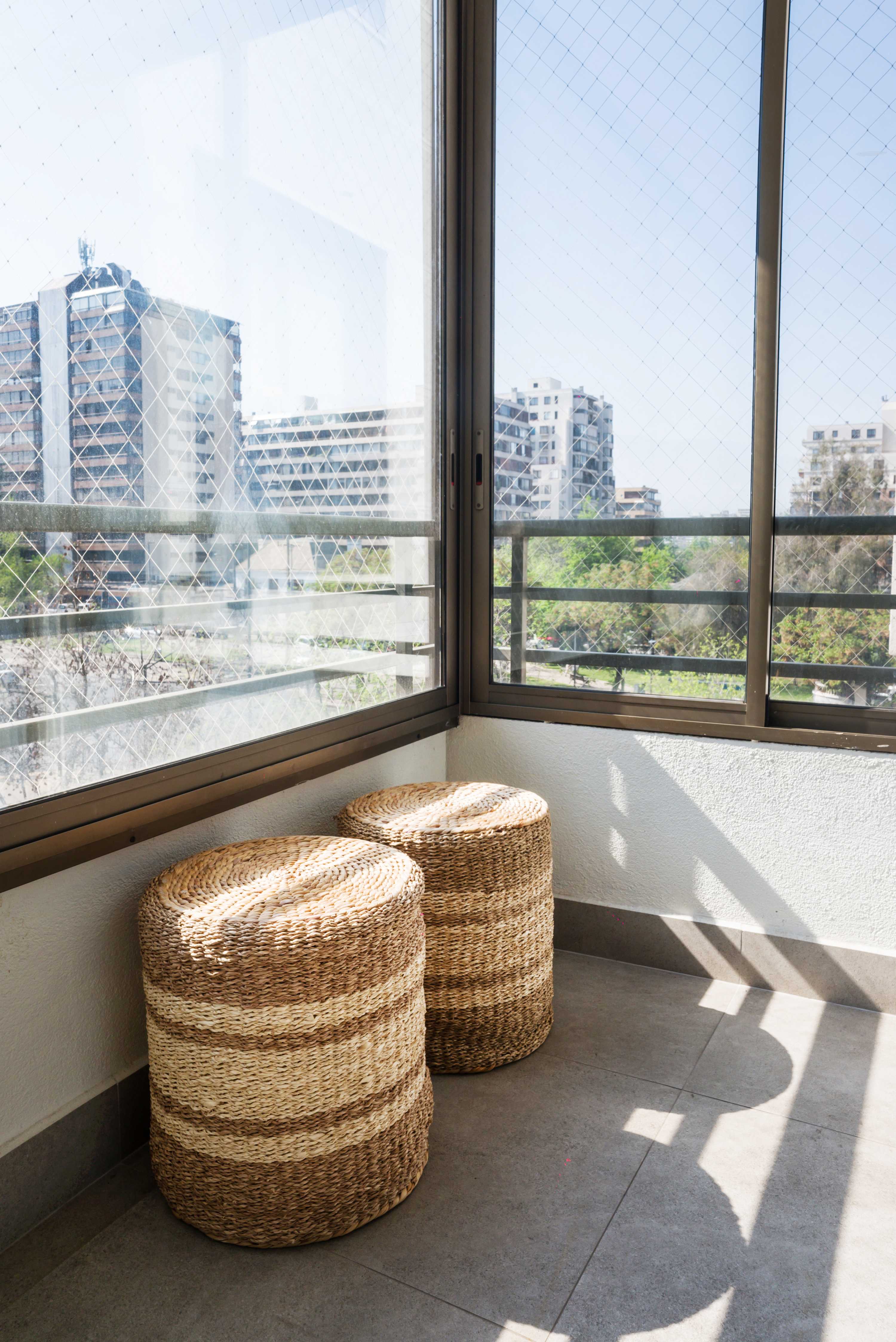 Relax on the cozy balcony with woven stools and enjoy stunning city views in the heart of Chile.