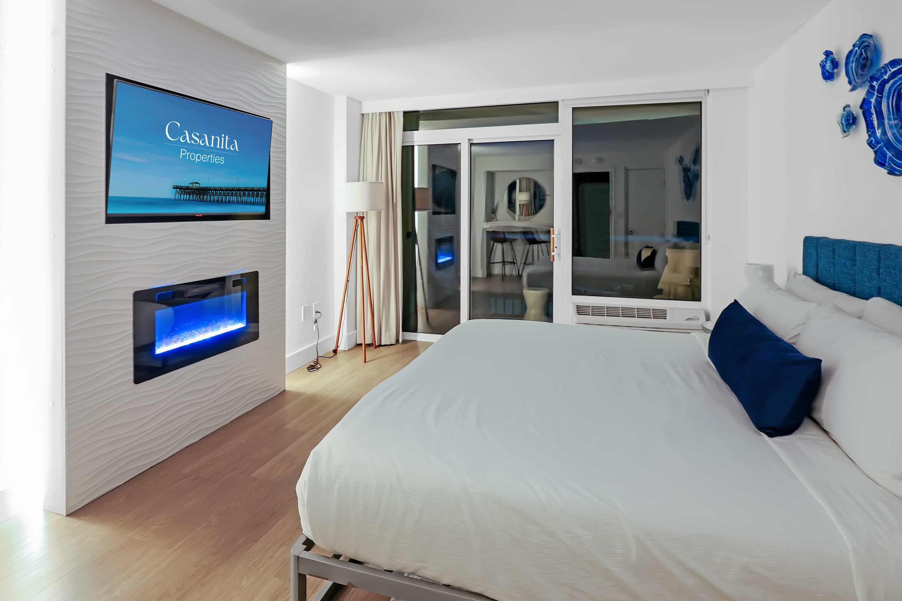 Wake up to breathtaking ocean views from your cozy bedroom retreat, featuring a plush bed, flat-screen TV, and private balcony access for the perfect blend of comfort and coastal charm.

