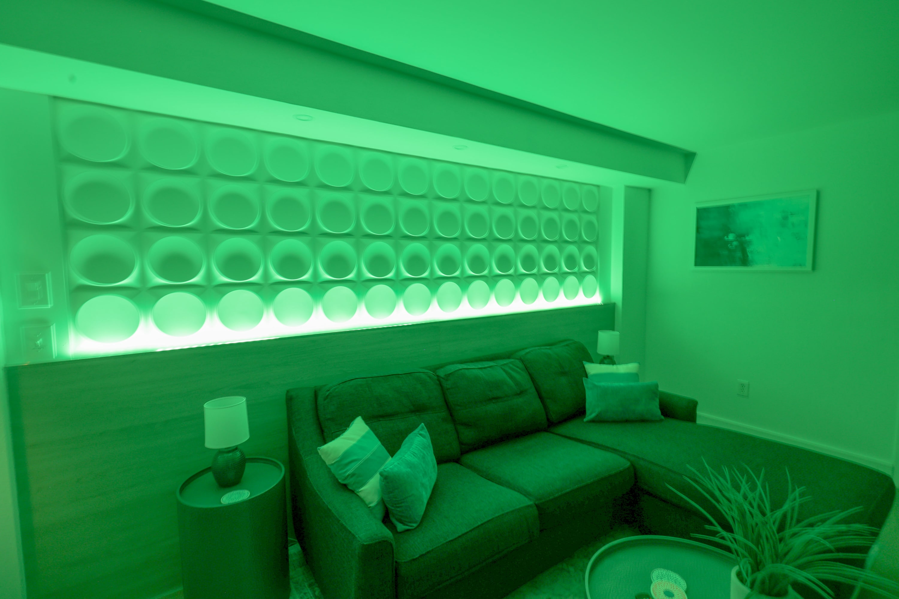Relax in this stylish living area featuring modern decor, warm lighting, and a cozy sectional sofa—perfect for unwinding after a day at the beach or enjoying a quiet evening with family and friends.