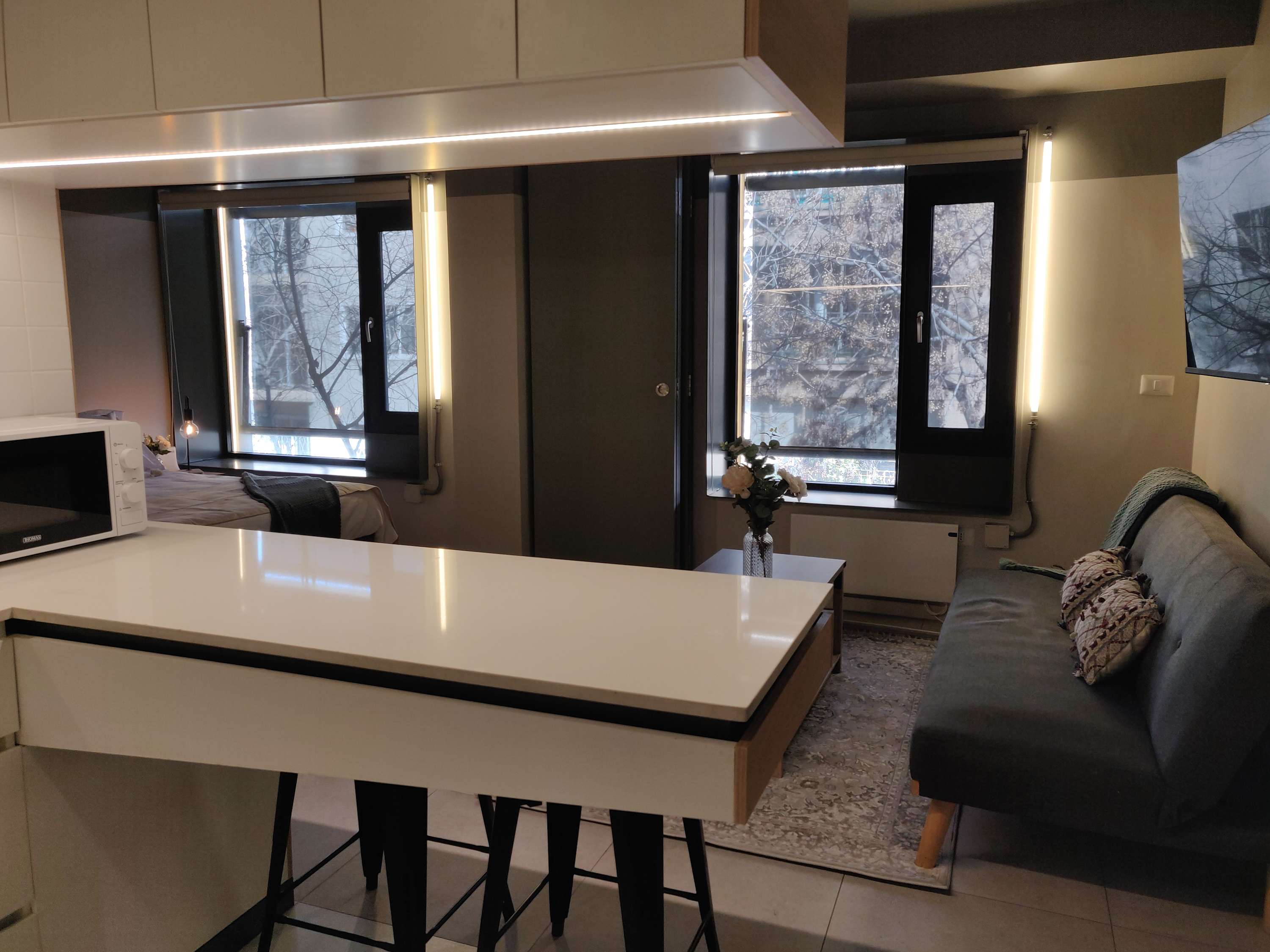 Cozy studio with modern amenities and large windows offering natural light, perfect for a relaxing stay in the heart of the city.