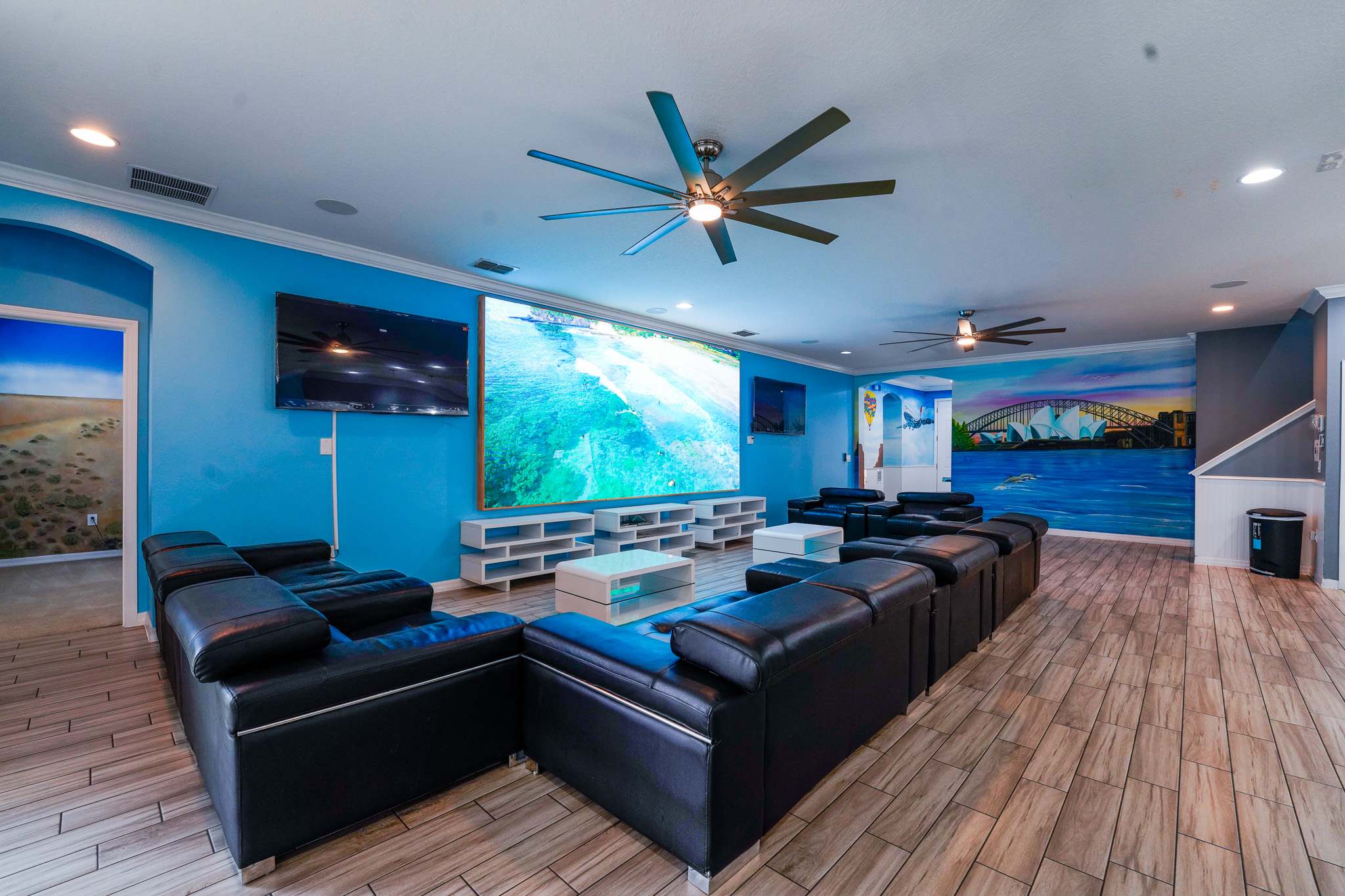 Experience ultimate entertainment in this vibrant game room with ample seating and a massive screen for movie nights.