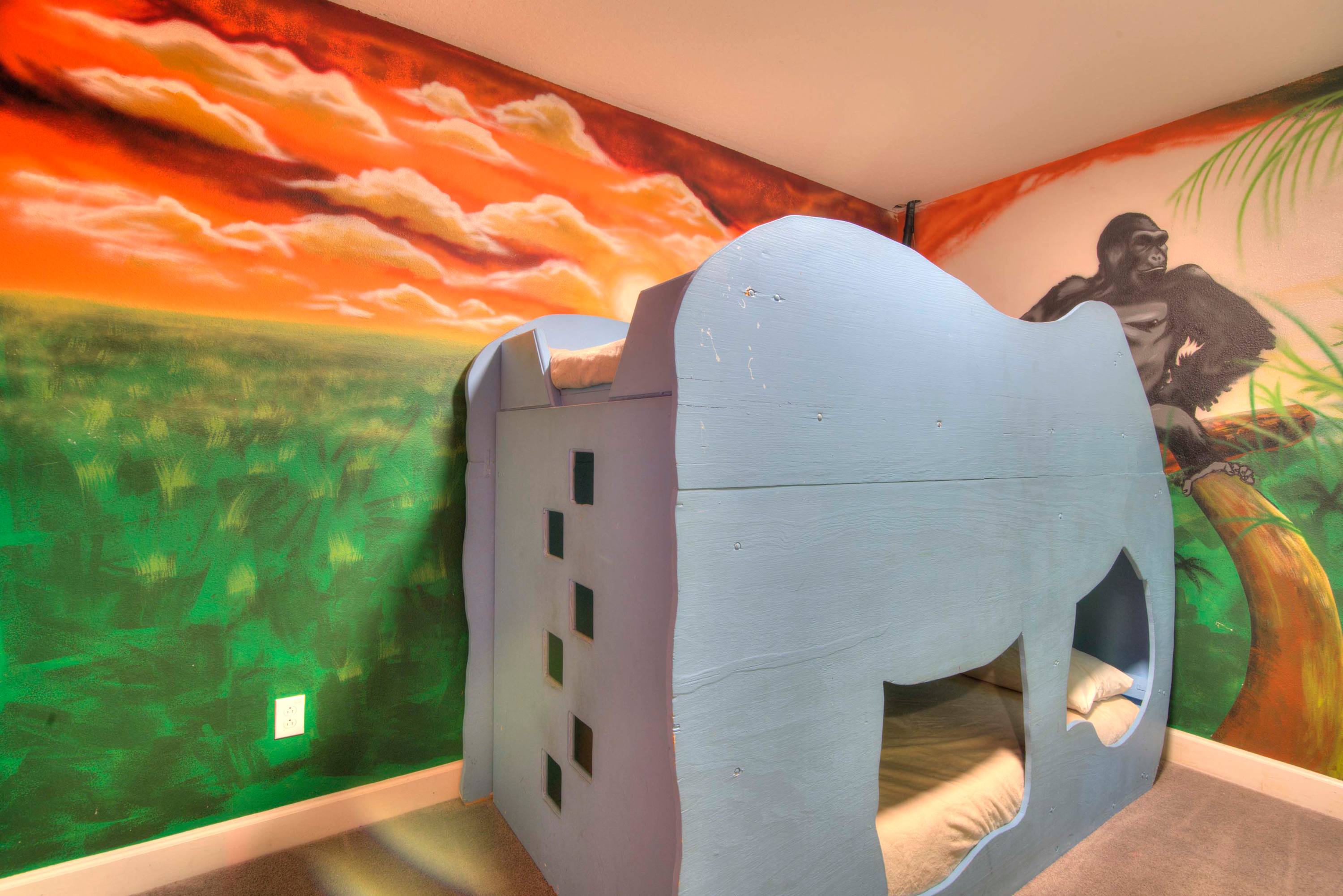 Delight your kids with this jungle-themed room featuring an elephant bunk bed and vibrant mural for an adventurous stay.