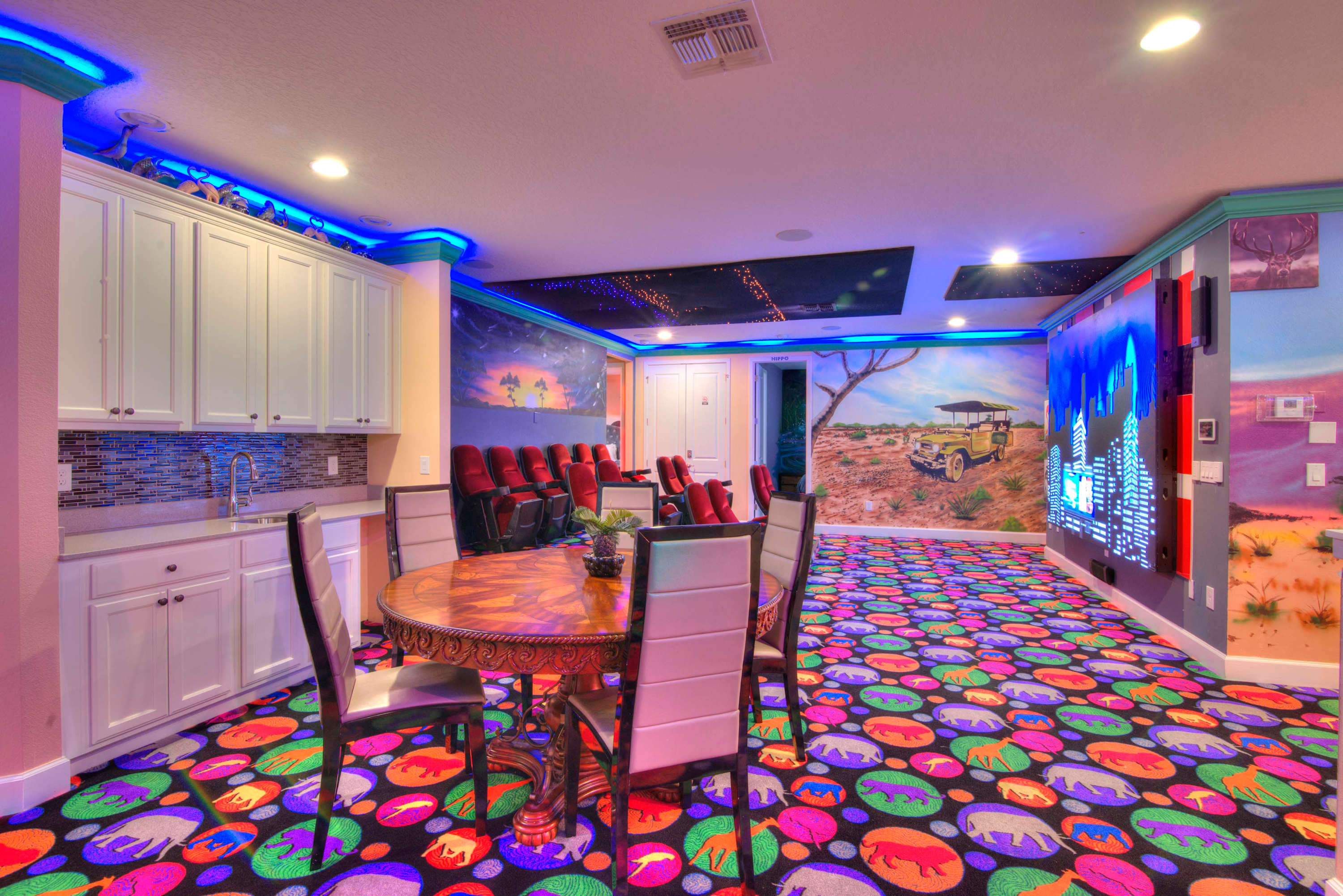 Enjoy a vibrant game room with theater seating, murals, and a kitchenette for ultimate entertainment.