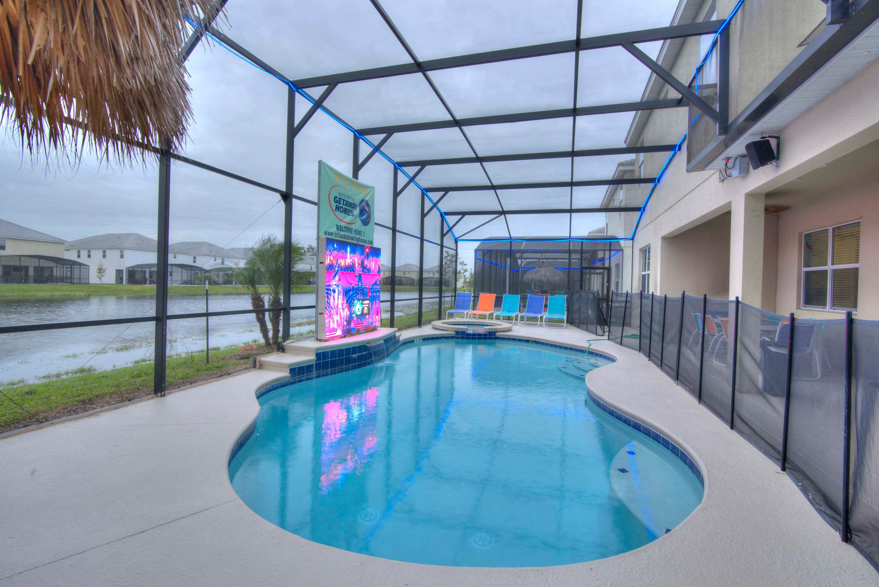 Relax by the private pool with vibrant seating and a stunning entertainment screen, perfect for unwinding and enjoying the view.