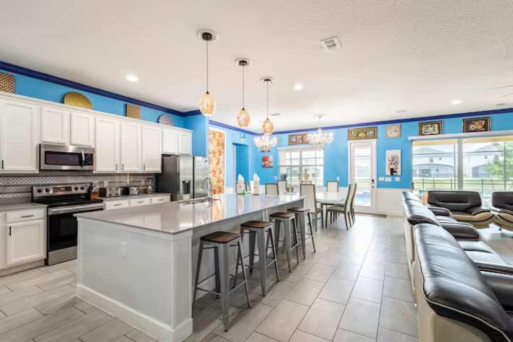 Entertain in style with this expansive kitchen featuring a large island, modern appliances, and vibrant decor, perfect for group gatherings.
