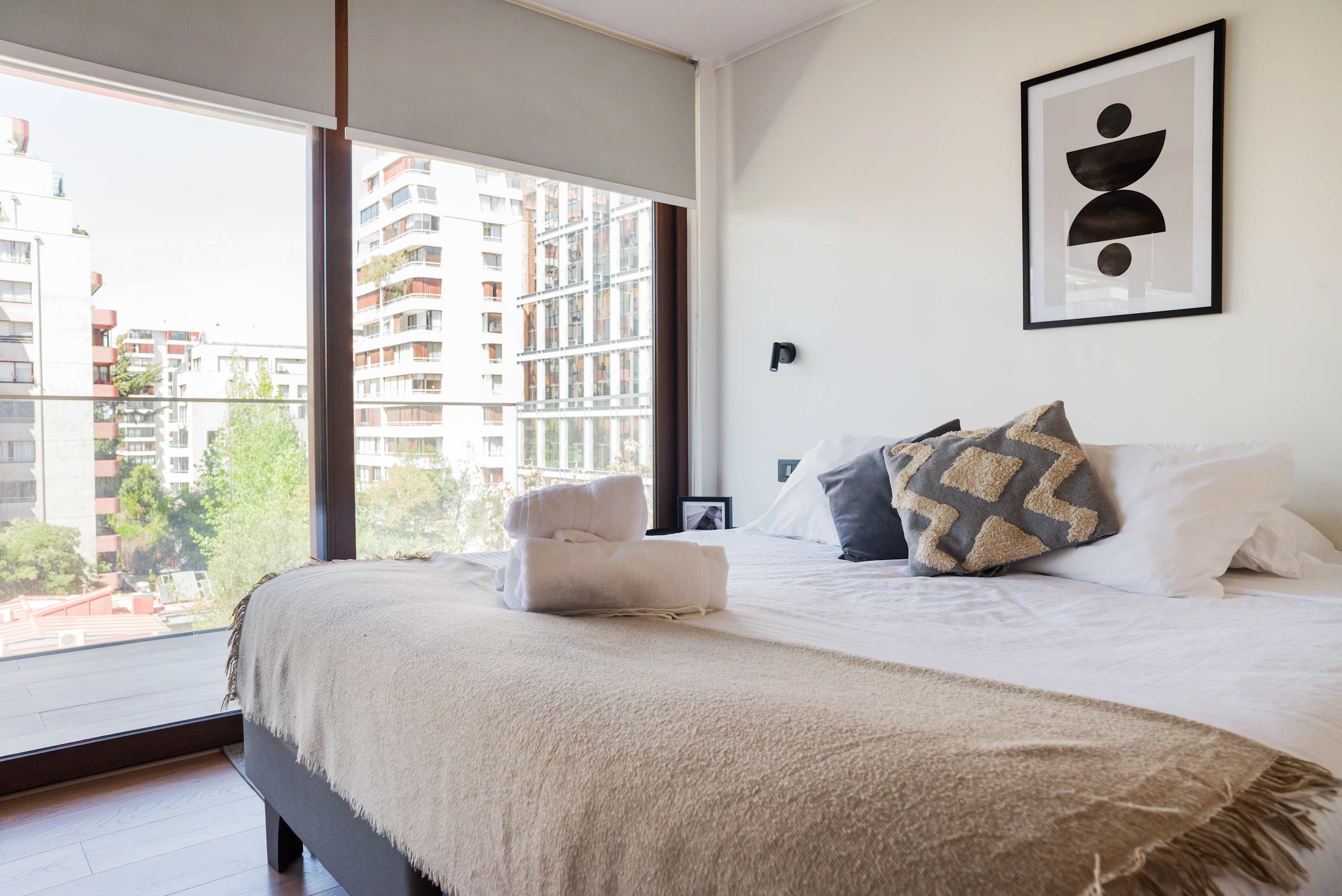 Relax in a cozy bedroom with stunning city views and modern decor, perfect for unwinding after a day of exploring.