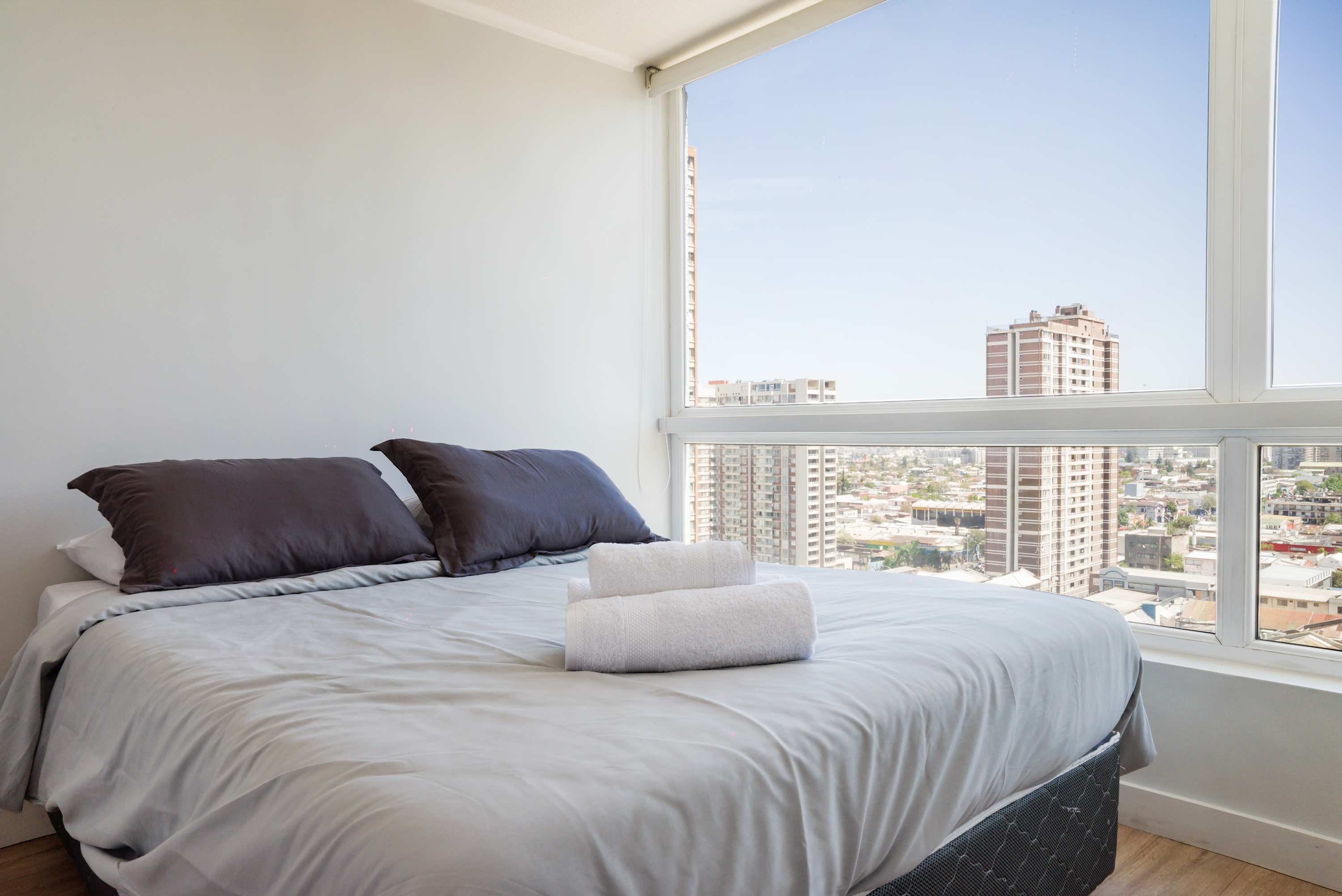 Relax in this cozy bedroom with breathtaking city views, perfect for unwinding after a day of exploring.