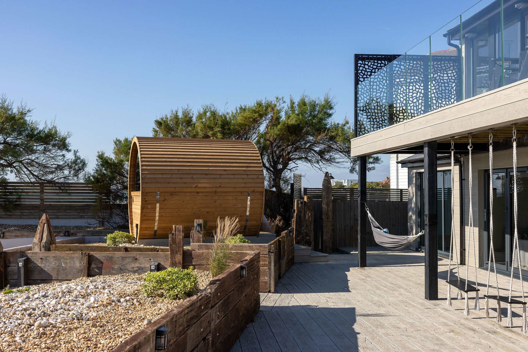 Newly laid decking surrounds the rear of the home, offering seating areas and direct beach access.