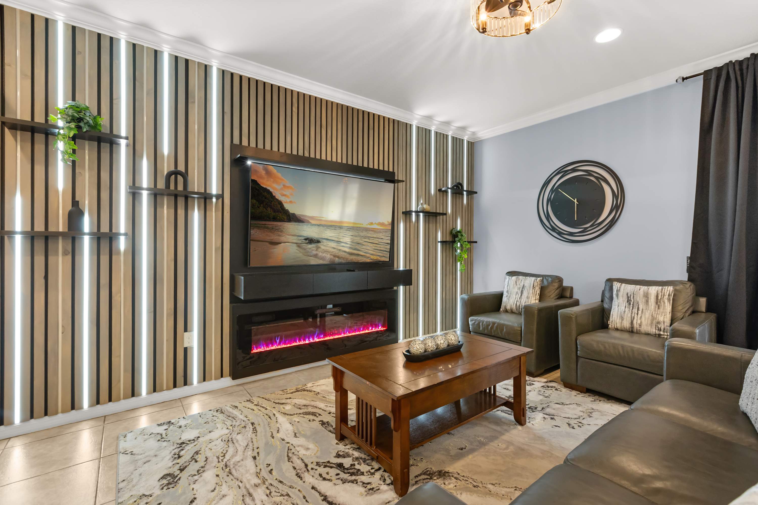 Open-Concept Lounge: Relax in the stylish main lounge featuring plush sofas, a large smart TV, and a stunning feature wall with modern lighting — perfect for movie nights or family hangouts.