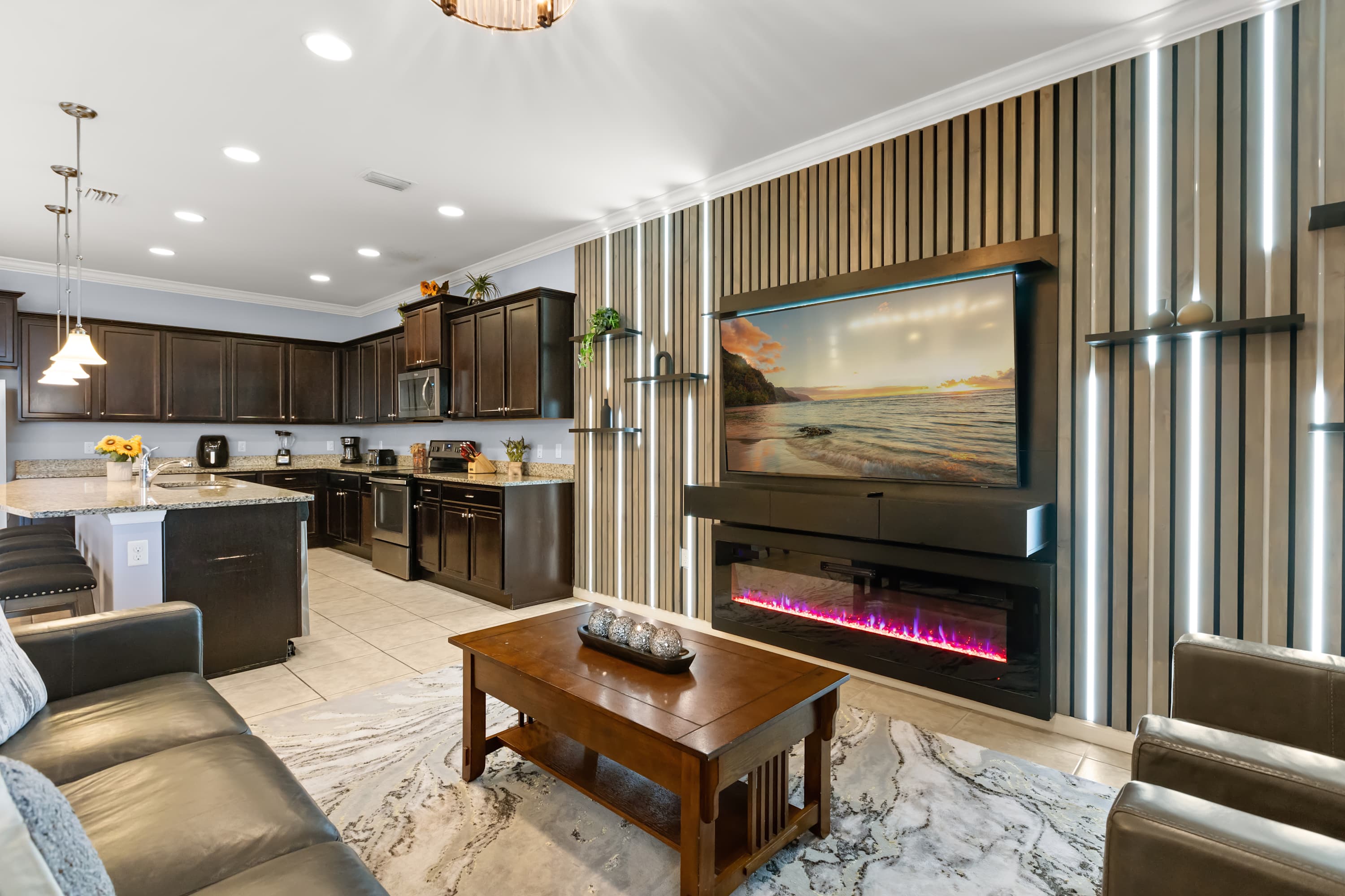 Open-Concept Lounge: Relax in the stylish main lounge featuring plush sofas, a large smart TV, and a stunning feature wall with modern lighting — perfect for movie nights or family hangouts.