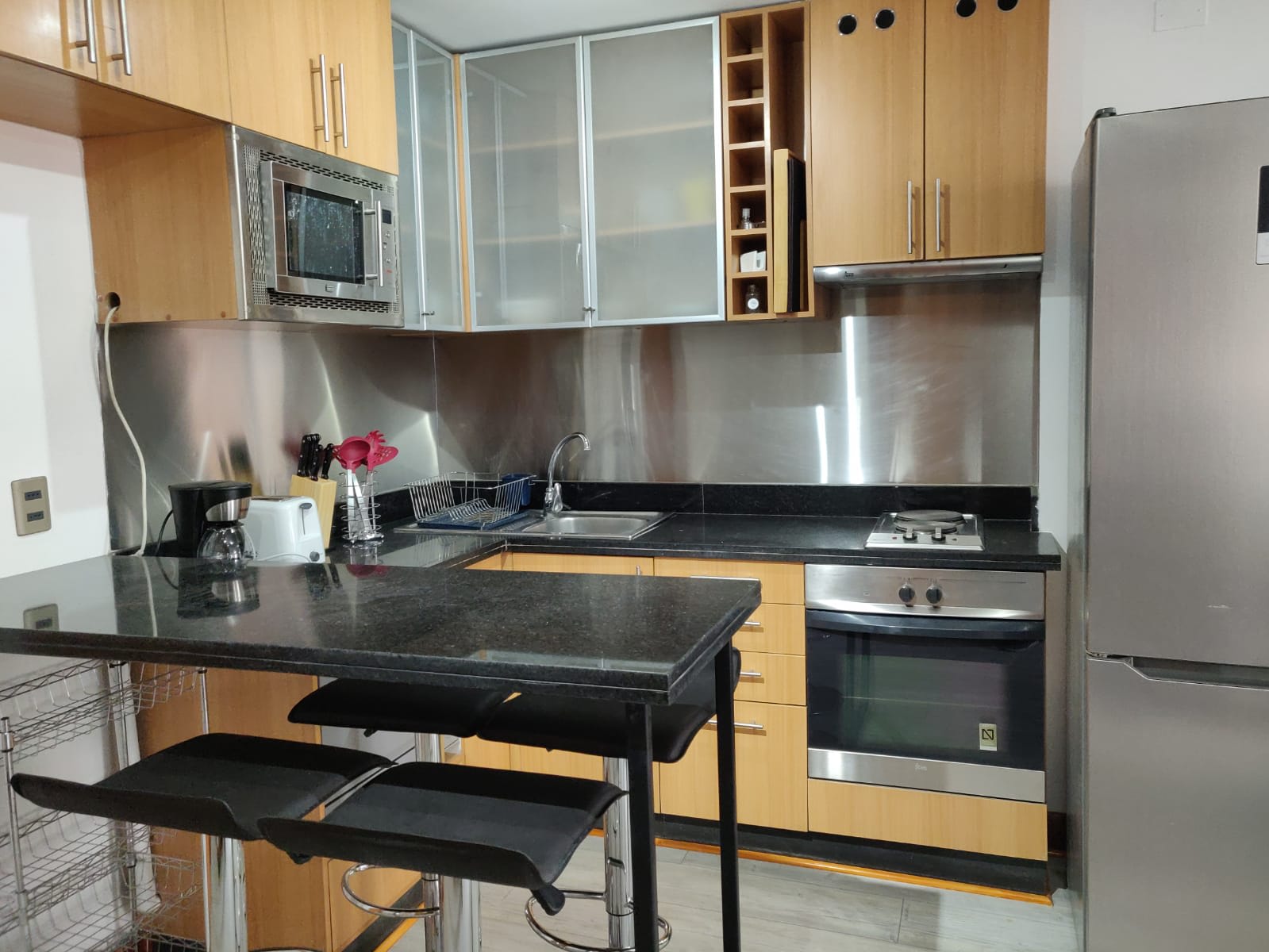 Sleek kitchen with modern appliances and cozy dining bar, ideal for intimate meals in a stylish setting.