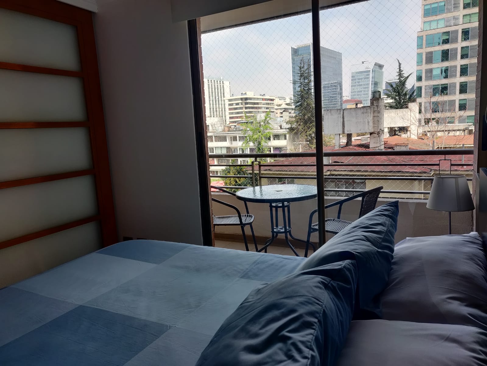 Relax in a cozy bedroom with a private balcony offering stunning city views, perfect for unwinding in Santiago.