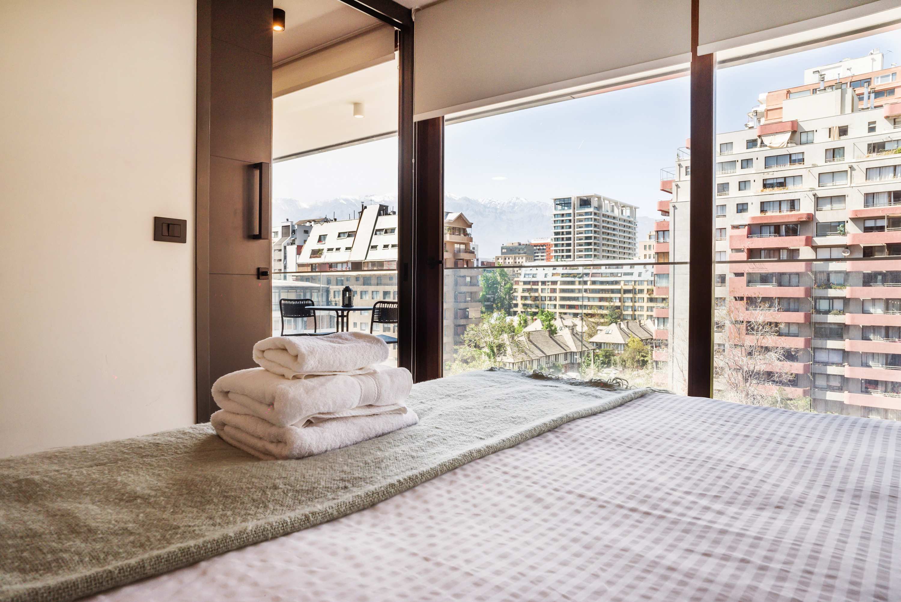 Relax in a cozy bedroom with stunning city and mountain views from your private balcony.