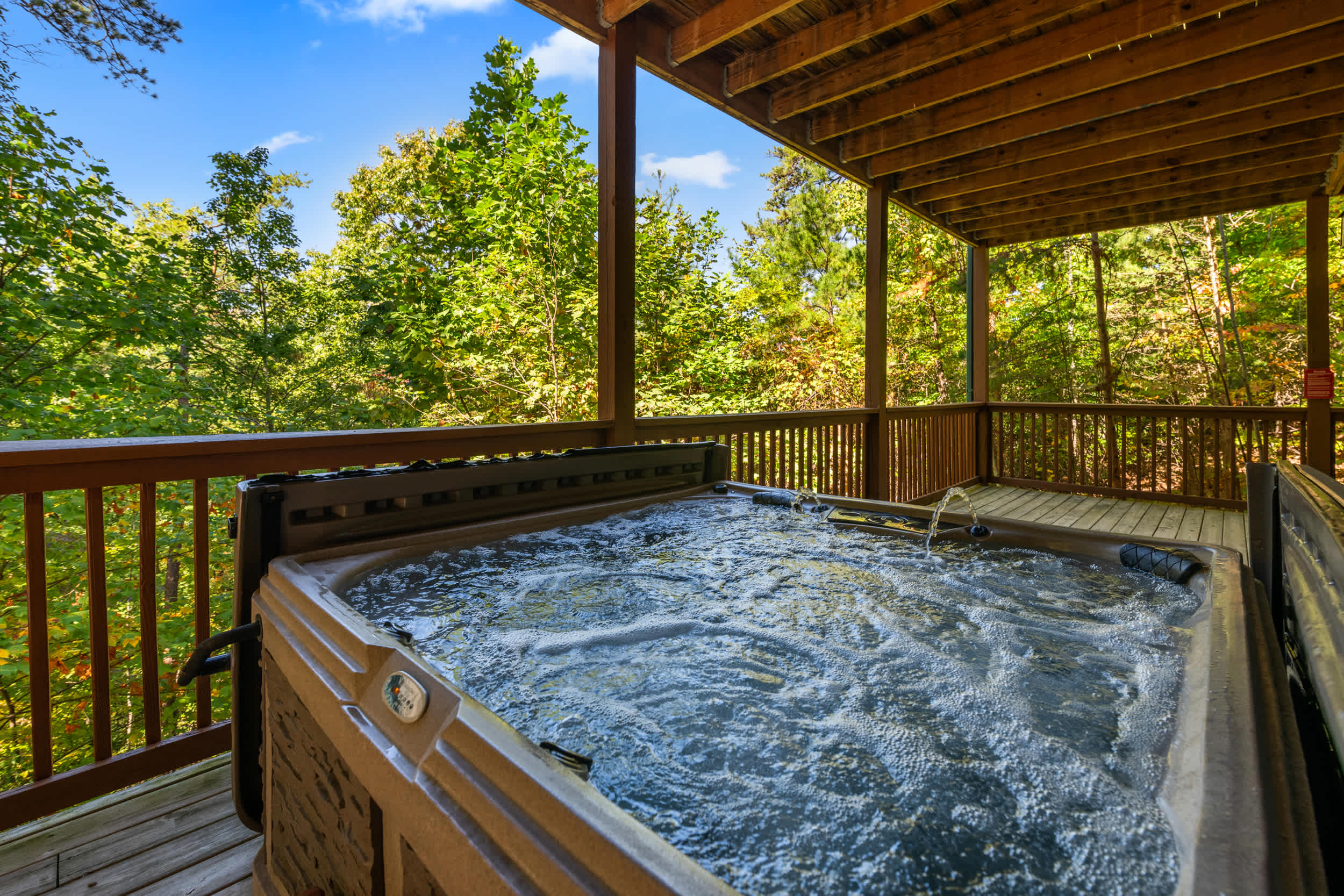 Relax in the hot tub on the covered lower deck amidst the trees.