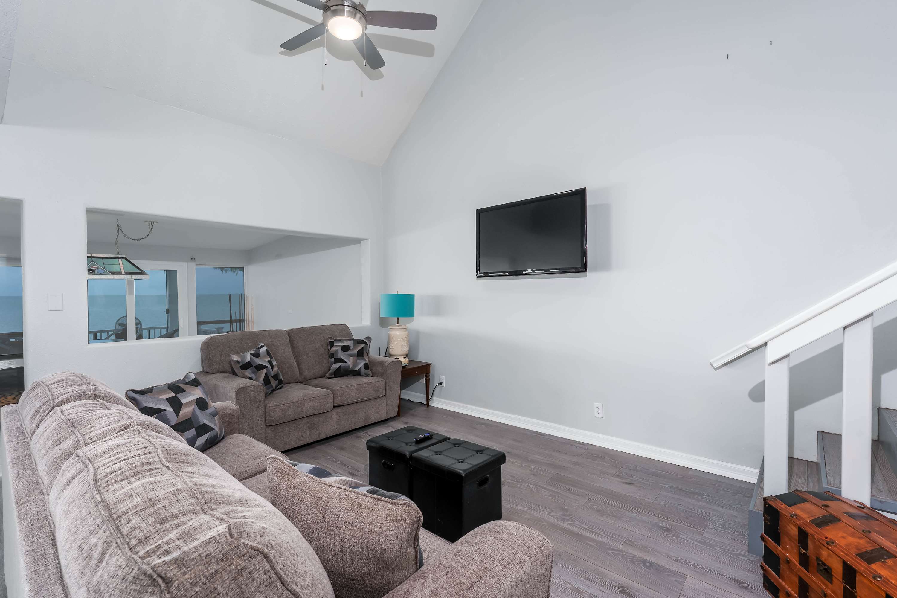 Bright & Spacious Living Room — Relax in the open-concept lounge with plush sofas, vaulted ceilings, and large windows framing breathtaking waterfront views.