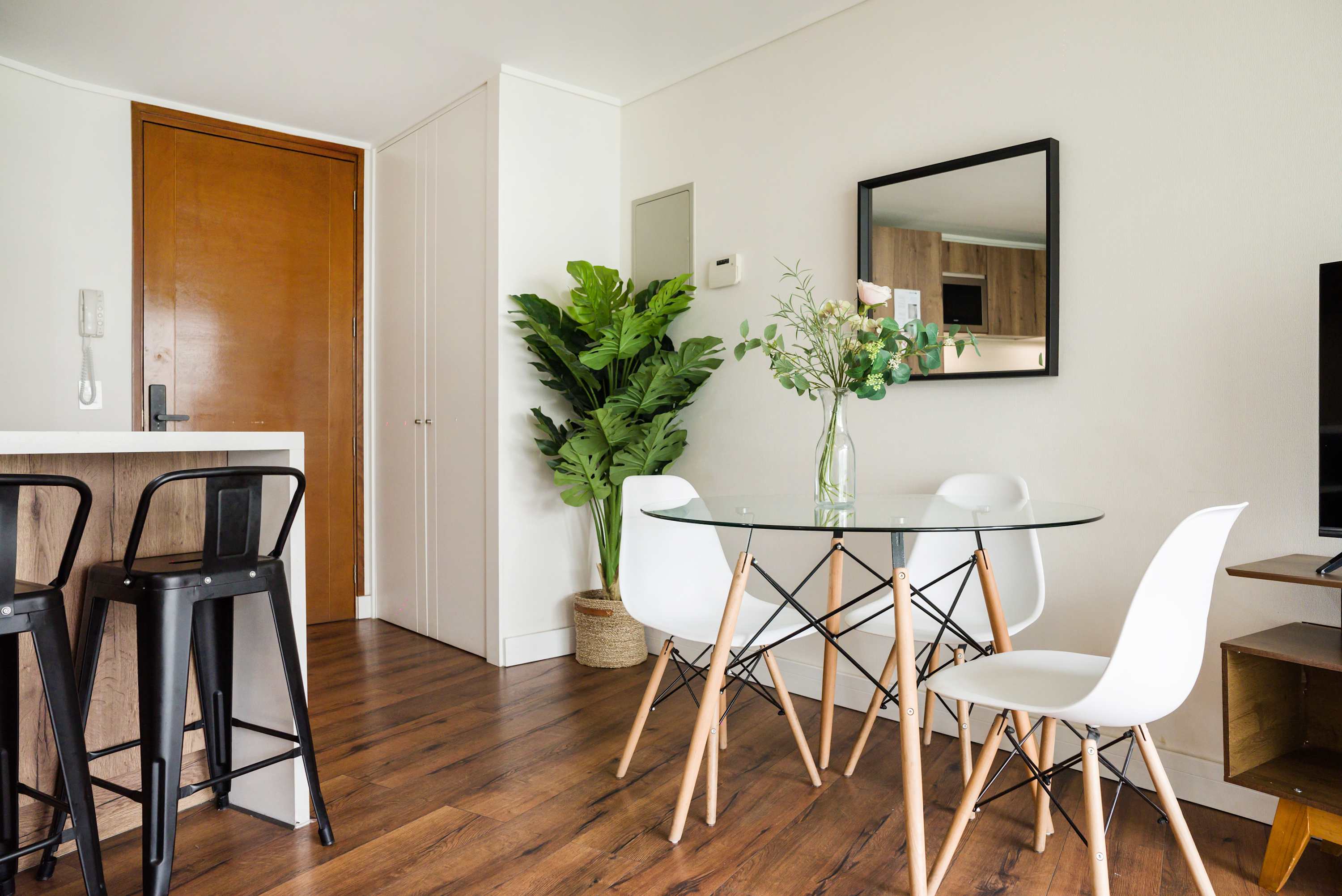 Stylish dining area with a glass table, modern decor, and natural light, ideal for intimate meals.