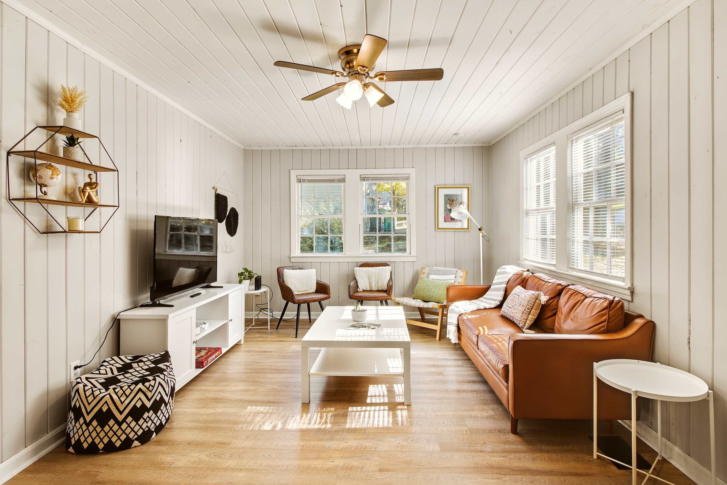 Bright and cozy living room with a stylish leather sofa and ample natural light, perfect for relaxation.