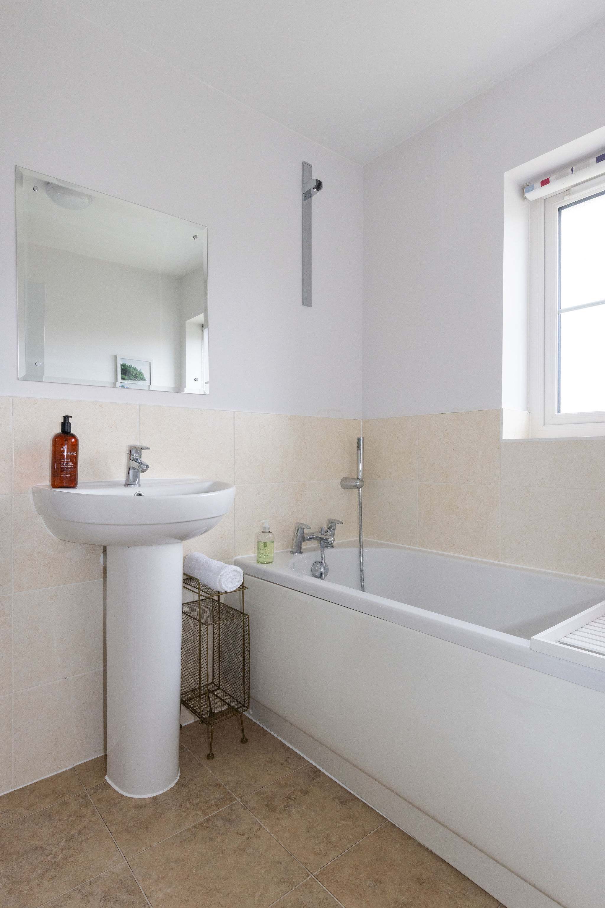 The family bathroom has a bath with handheld shower head, as well as sink, WC and heated towel rail.
