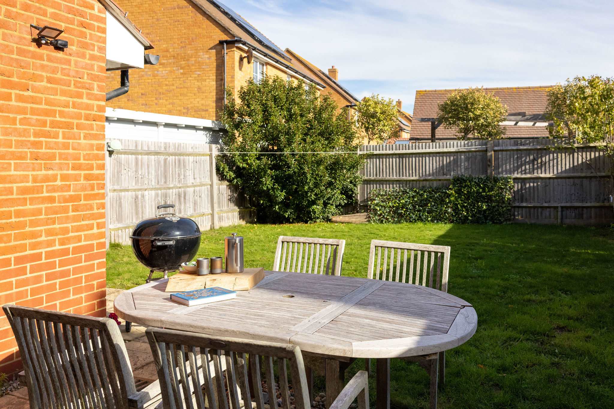 The sunny, enclosed garden with dining furniture and BBQ.