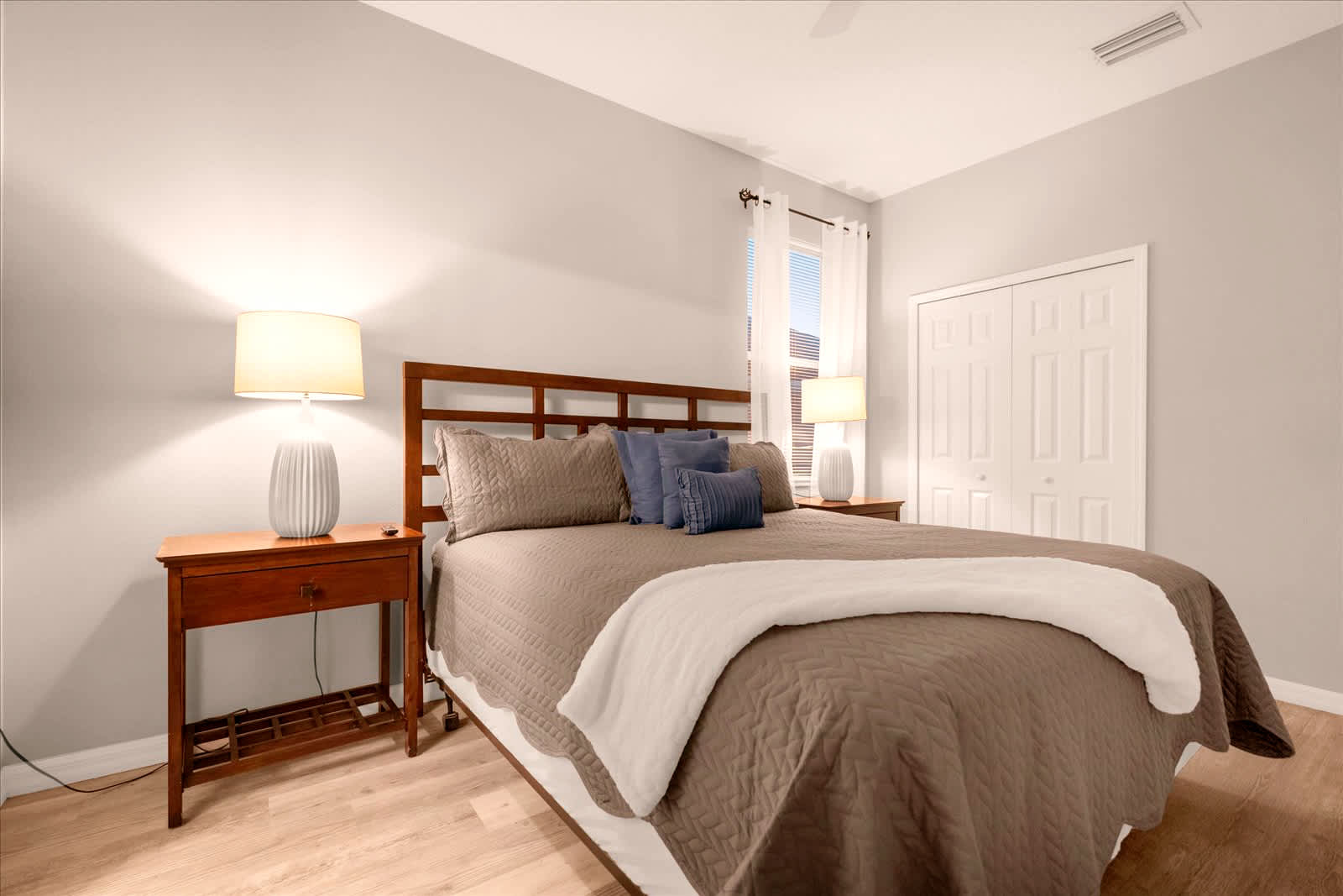 Relax in this inviting bedroom with plush bedding and warm lighting, perfect for a restful night's sleep.