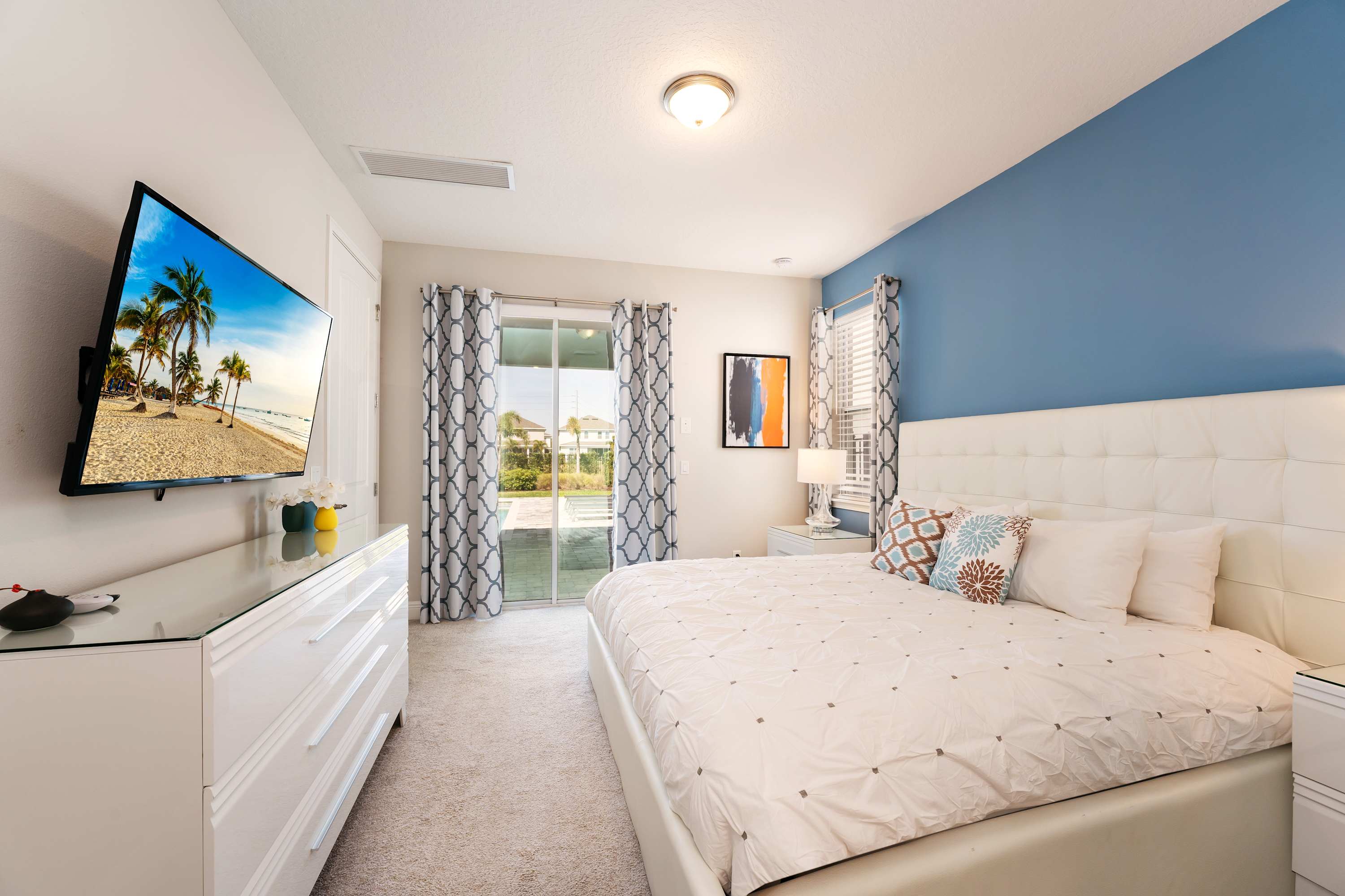 Relax in this stylish bedroom with plush bedding and direct access to a serene outdoor patio, perfect for unwinding.