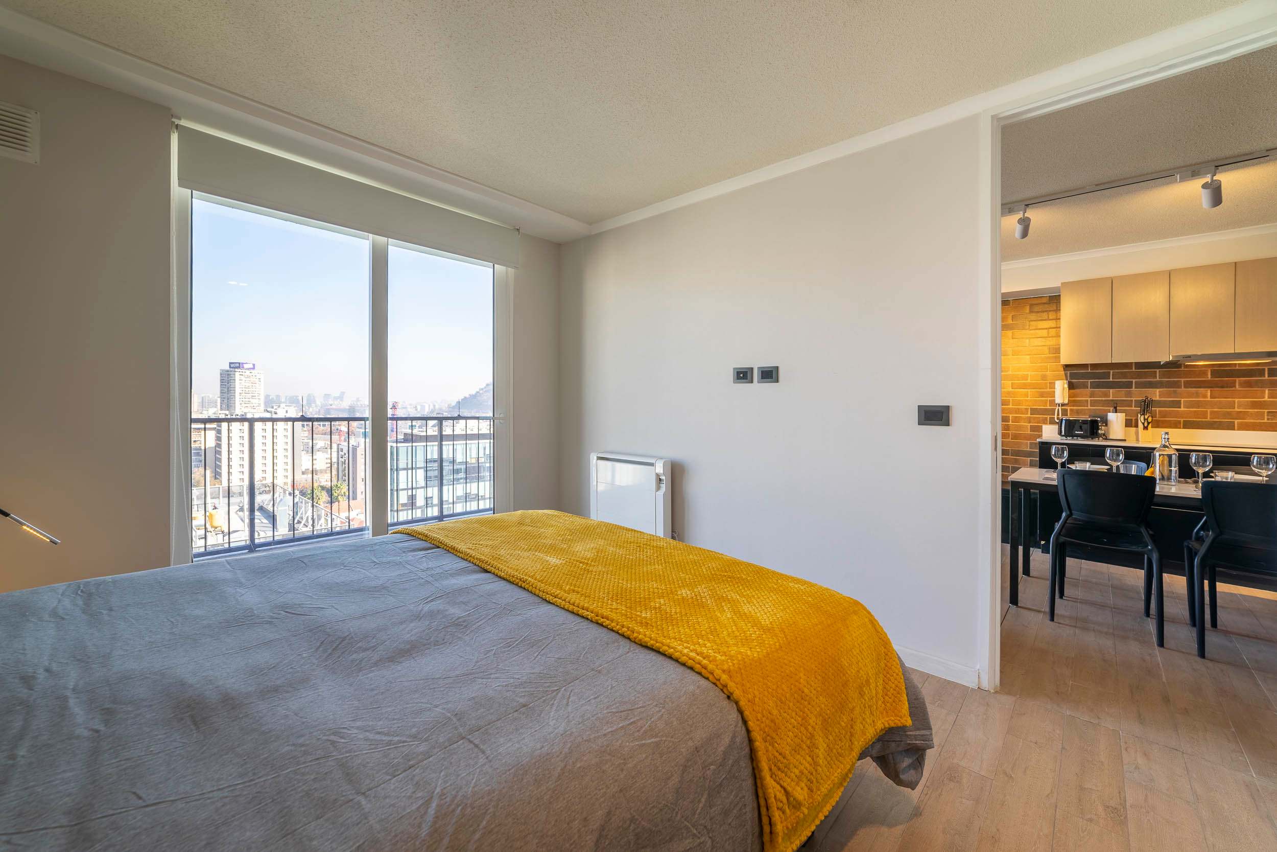 Cozy bedroom with stunning city views and a modern kitchen, perfect for a relaxing stay.