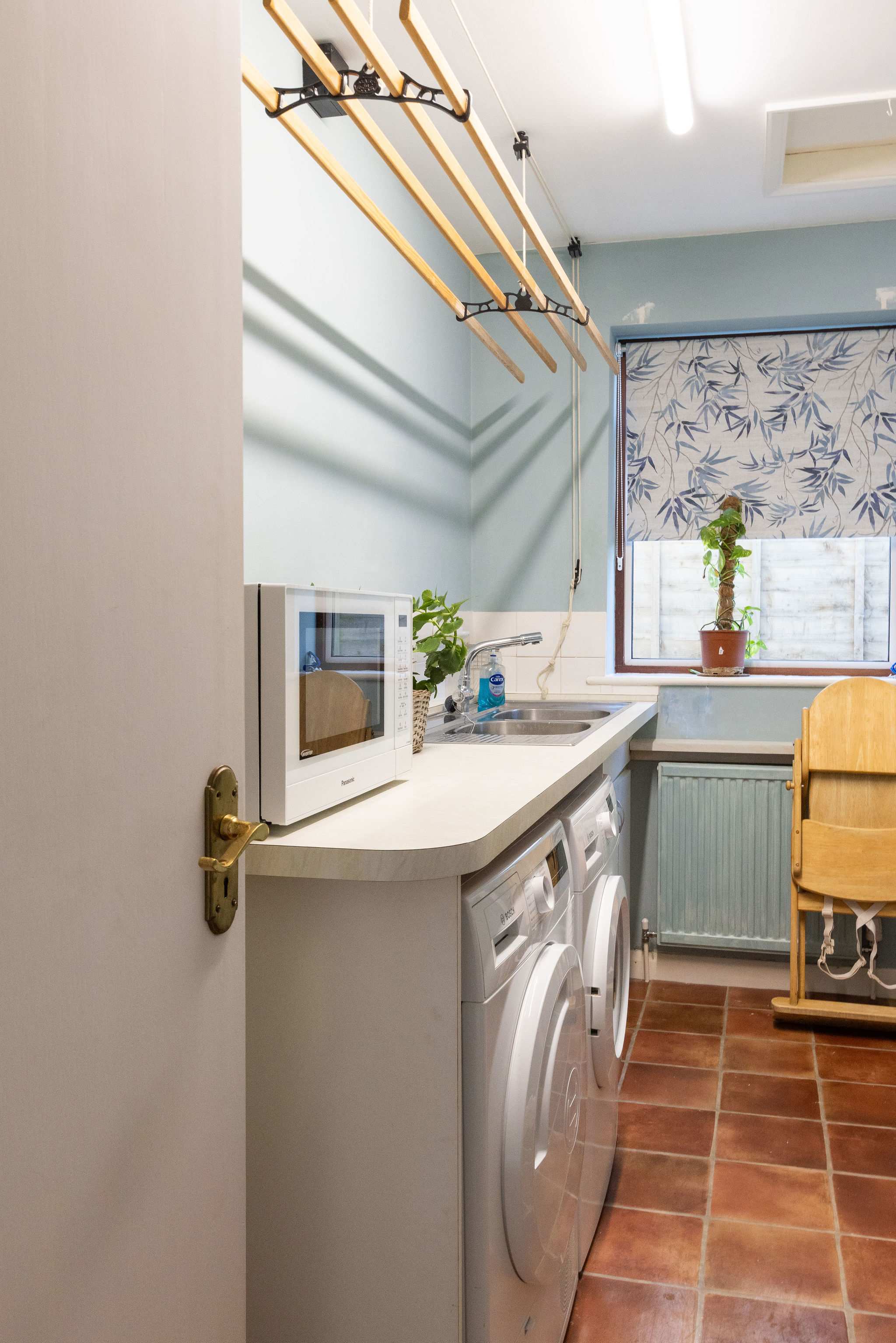 A separate utility room with microwave, washing machine, dryer and children's high chair.