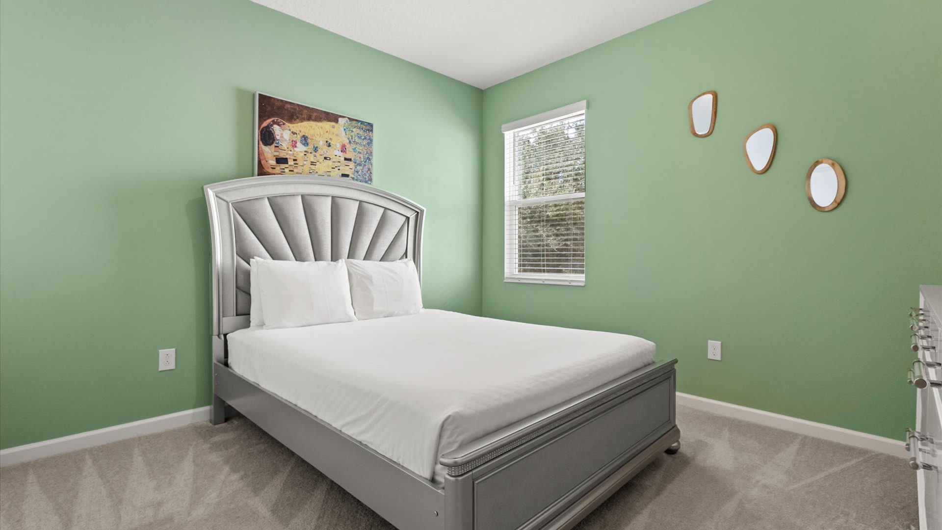 Bedroom 5 – Queen Suite: A queen bedroom with a soft green accent wall and elegant furnishings, perfect for unwinding after a fun-filled day.