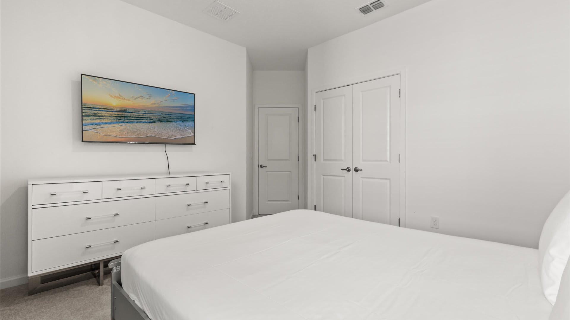Bedroom 5 – Queen Suite: A queen bedroom with a soft green accent wall and elegant furnishings, perfect for unwinding after a fun-filled day.