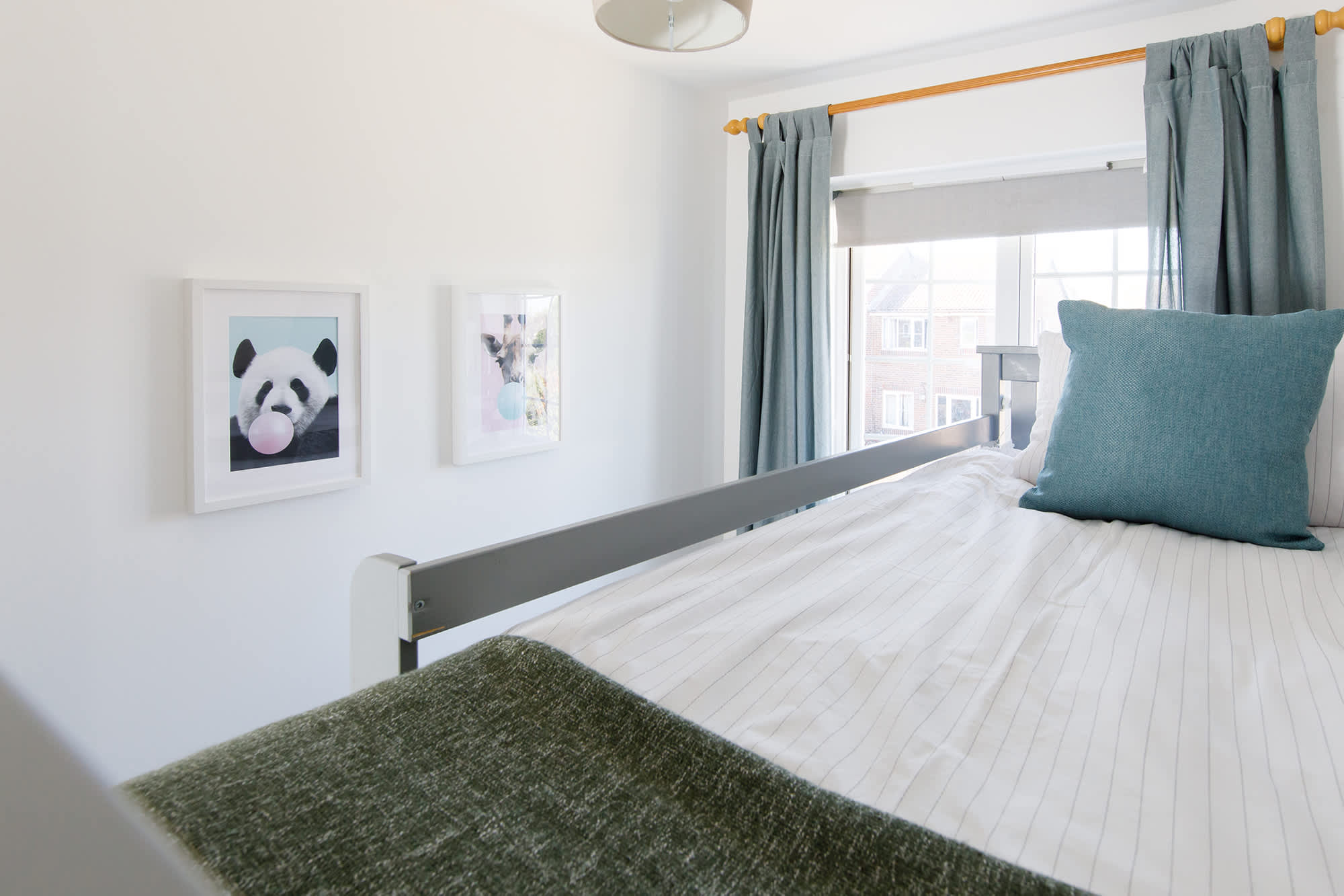 The children's bunk room has lovely pillows, throws and fun wall prints.