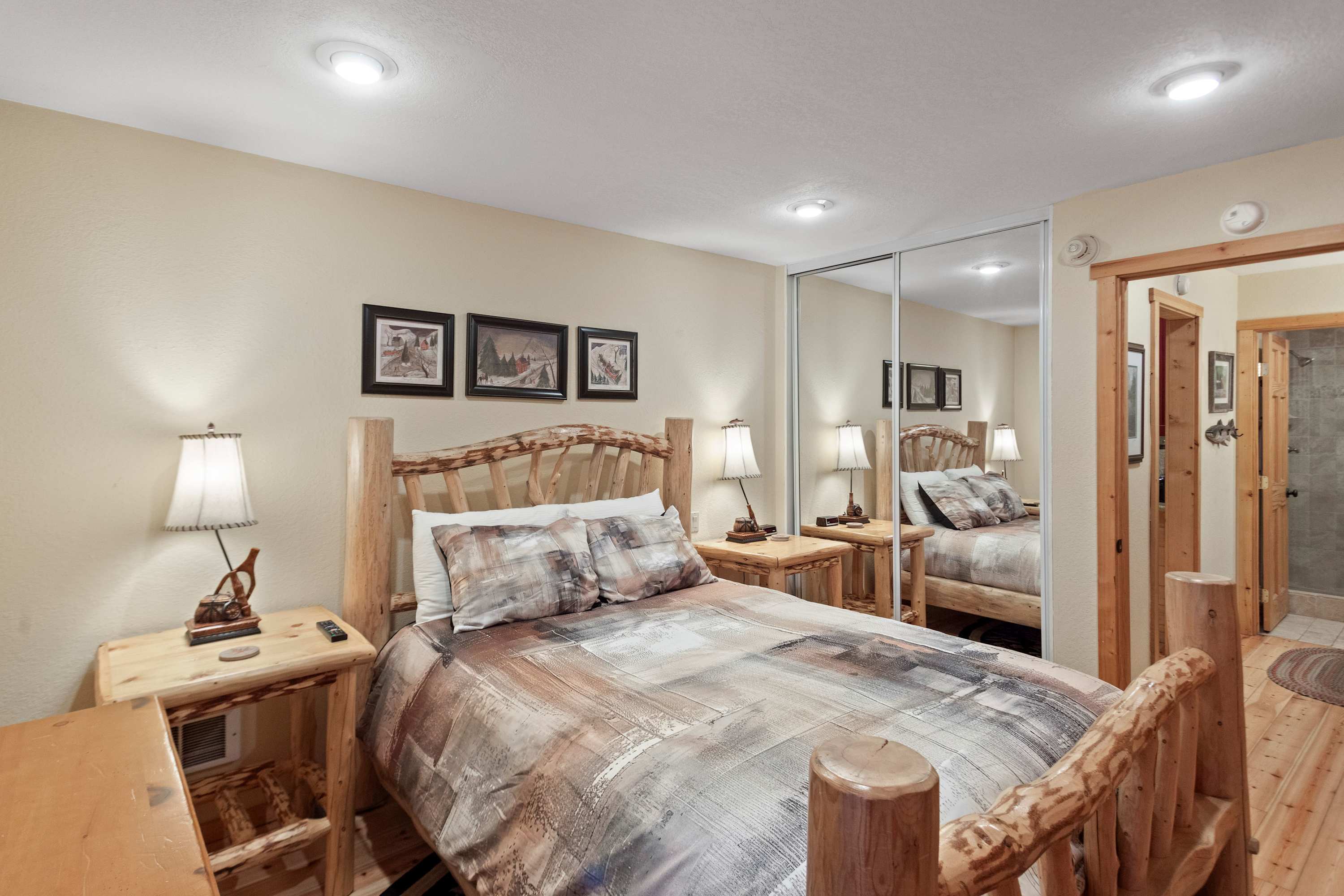 Cozy Queen bed, rustic pine frame, mirrored closet, and wall-mounted TV.