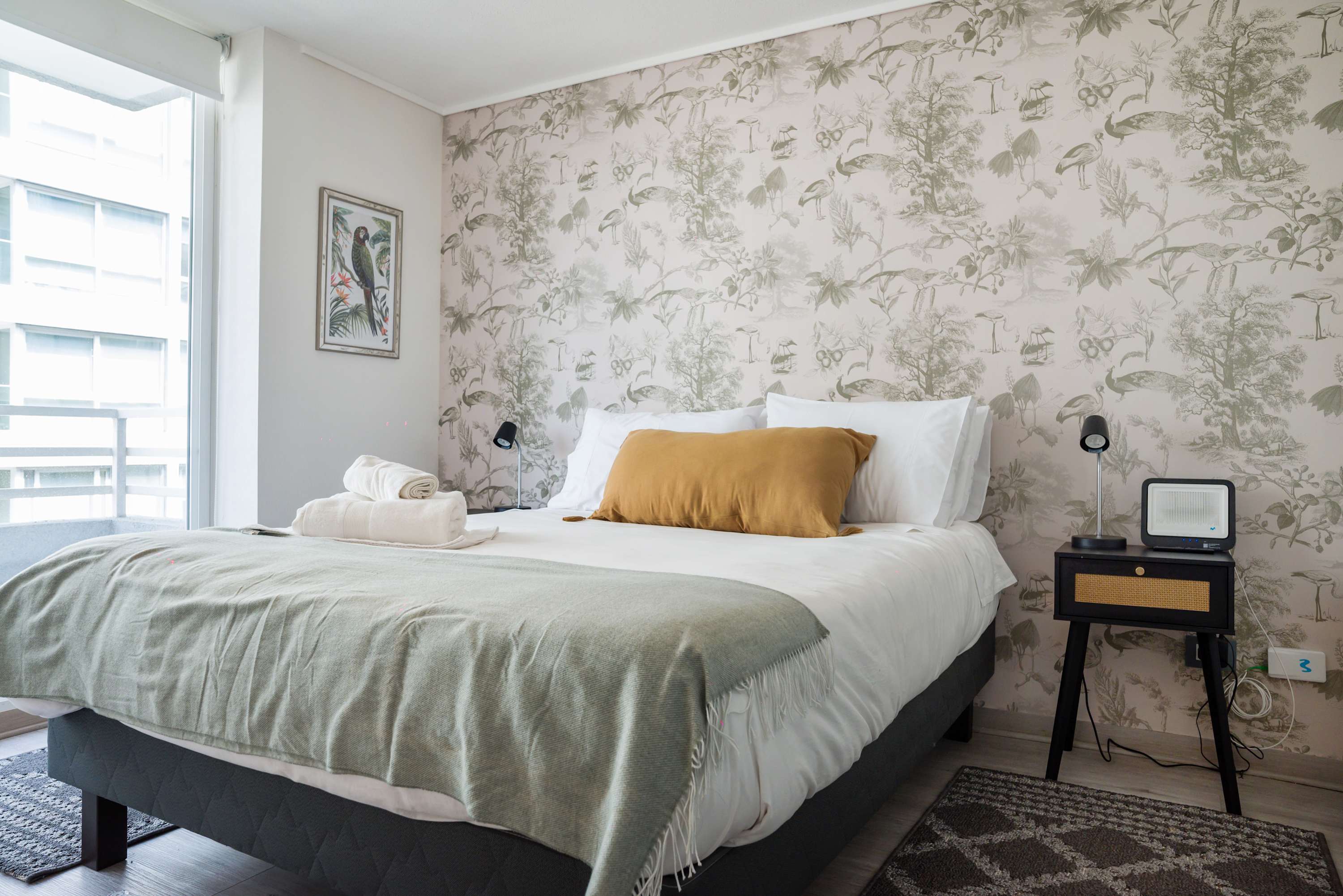 Cozy bedroom with nature-inspired decor and ample natural light, perfect for a relaxing stay.