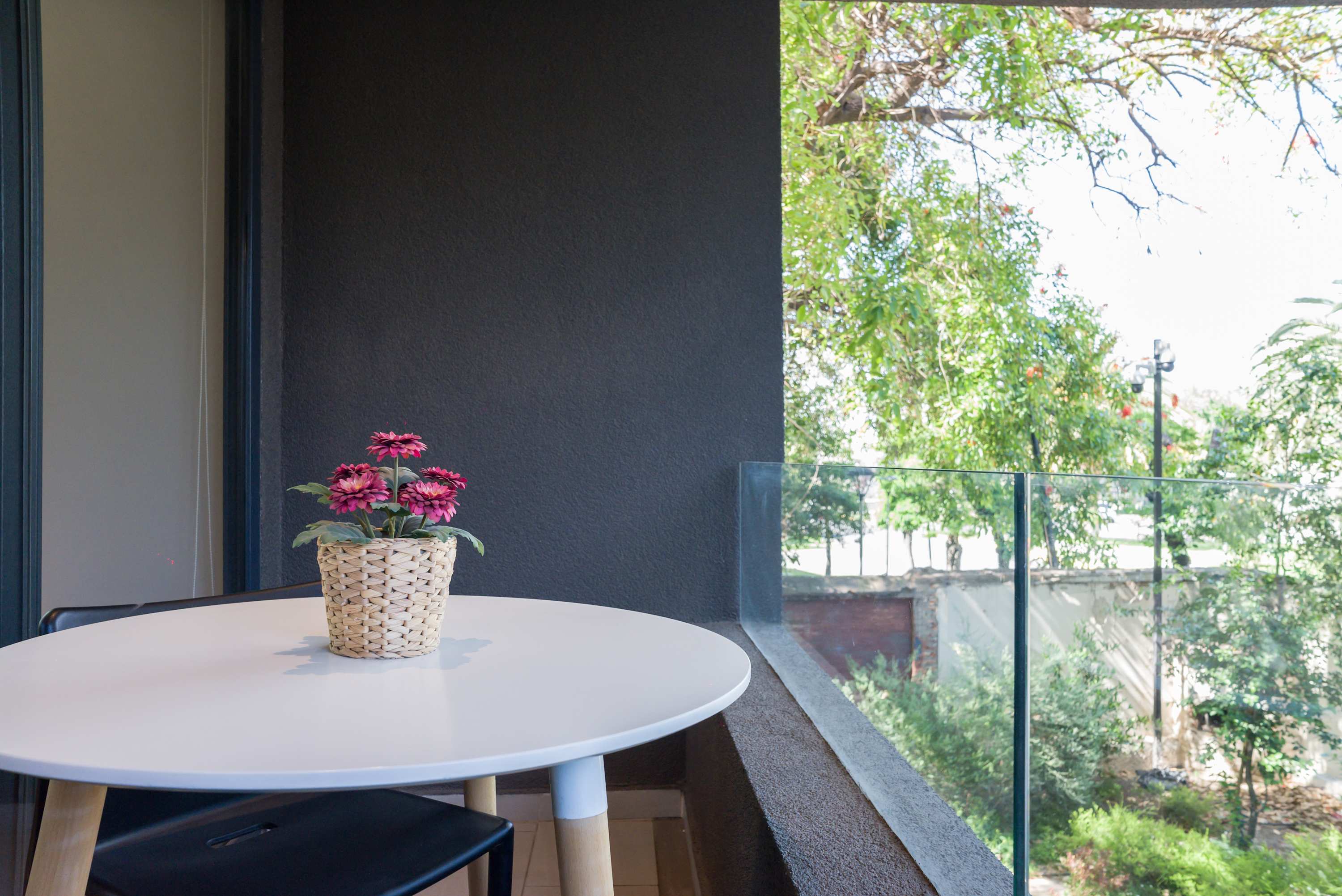 Enjoy your morning coffee on this serene balcony with a lush garden view, offering a peaceful retreat.